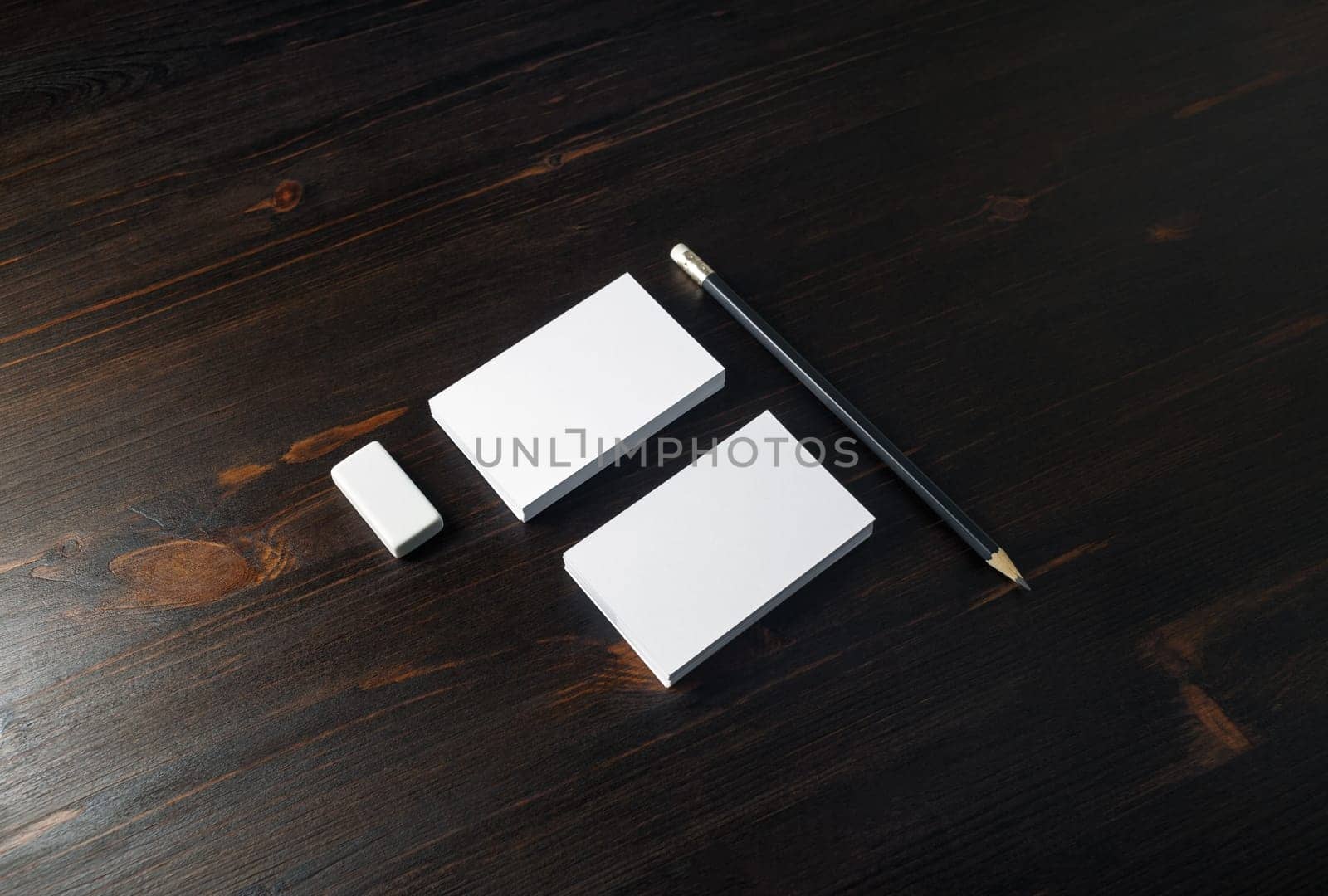 Blank business cards, pencil and eraser on wooden background. Stationery template for placing your design.