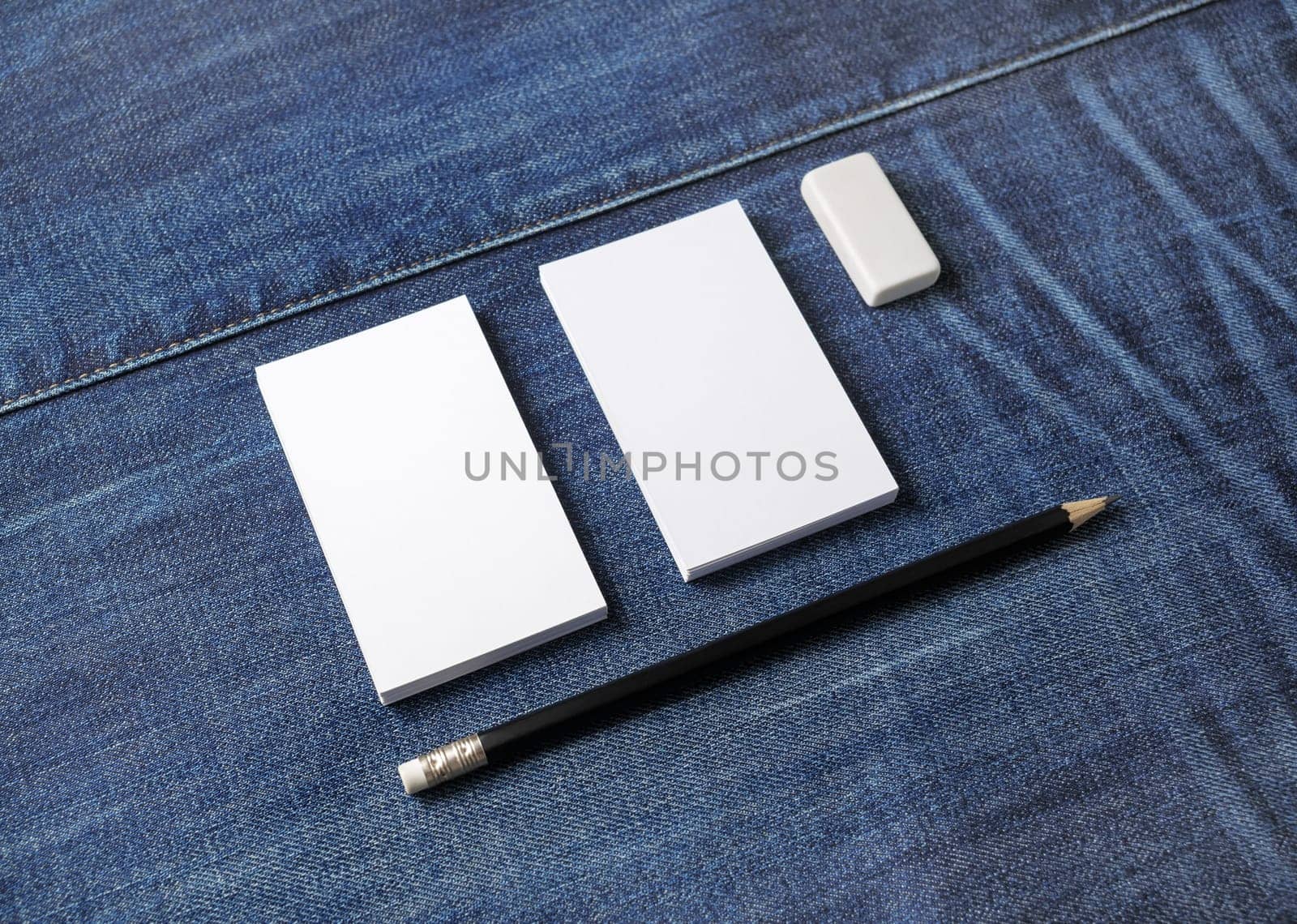 Photo of blank business cards, pencil and eraser on denim background. Stationery mock up. Template for placing your design.