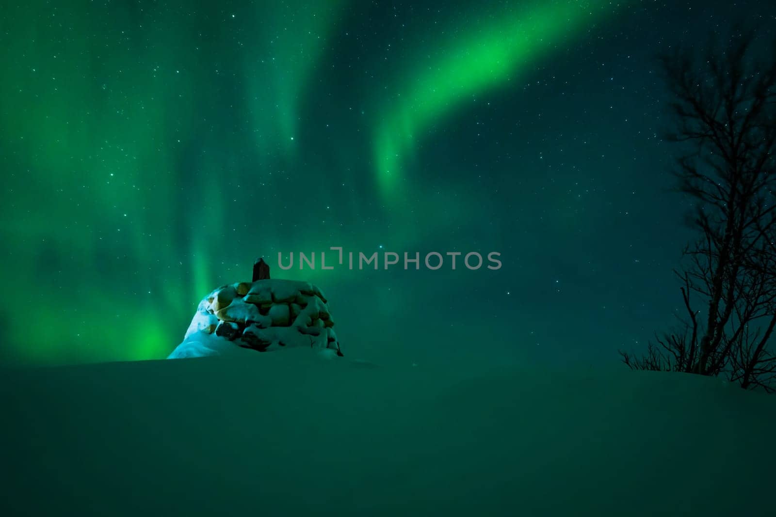 Awesome display of aurora borealis northern lights above the stone marker on the border between Finland and Norway