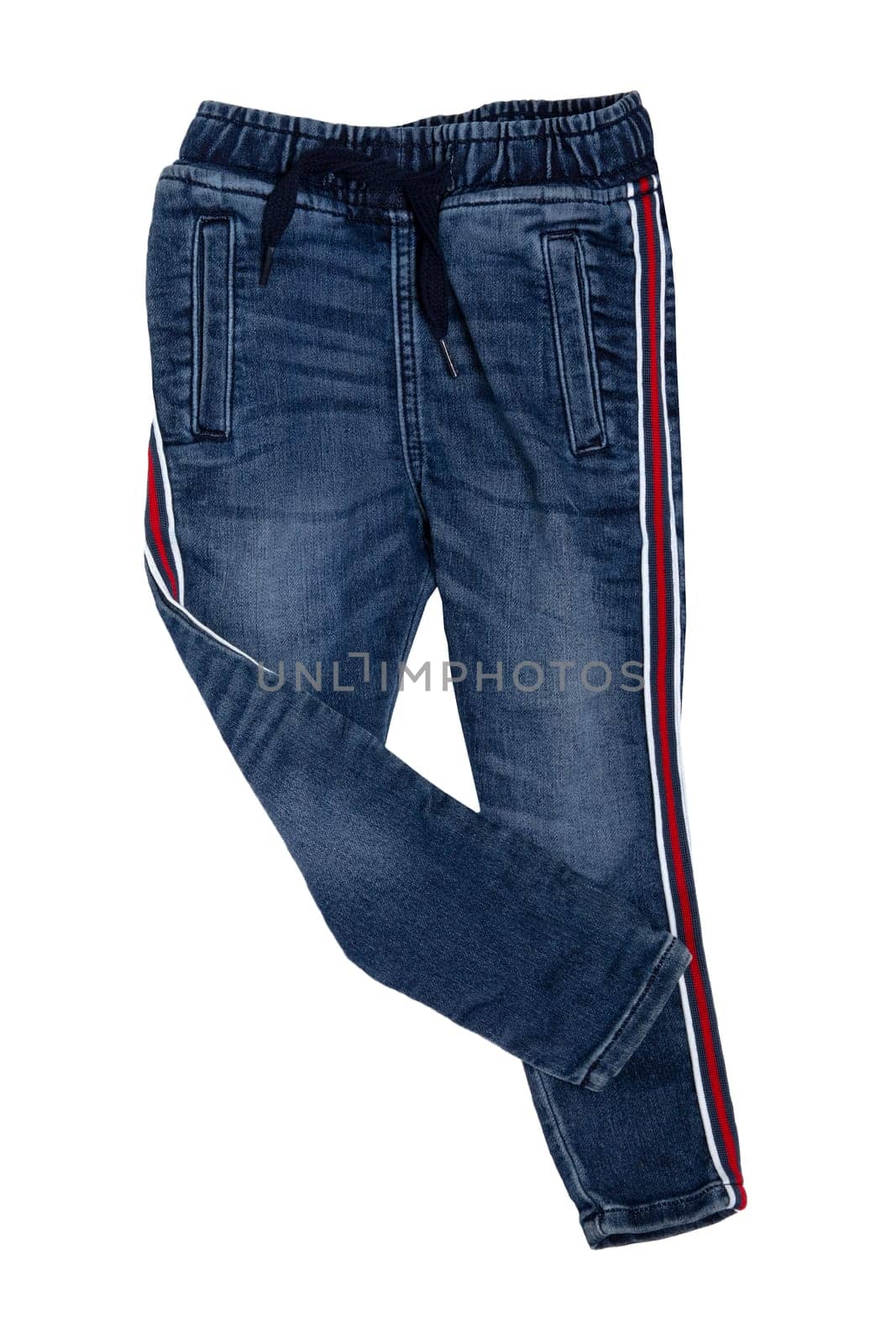 Fashionable denim clothes. Trendy stretch blue jeans trousers with lateral red stripes isolated on a white background. Fashionable jeans for child boy.