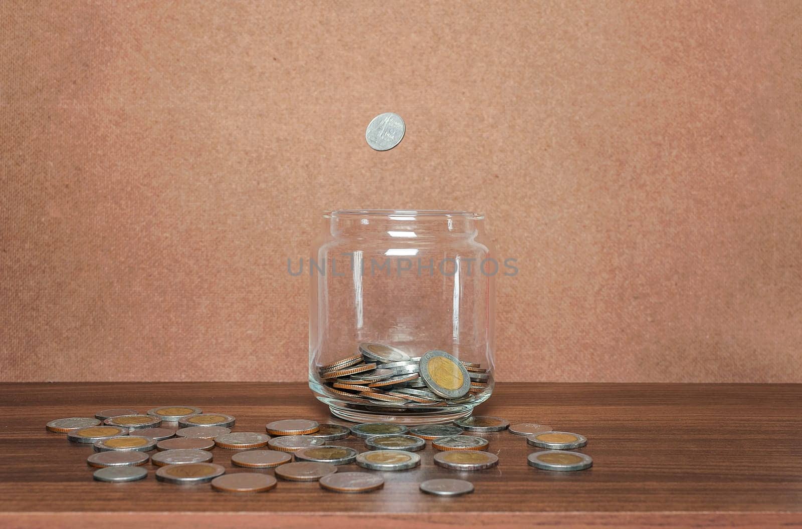 Save money and account banking for finance business concept, Coin in bottle and fall on brown background