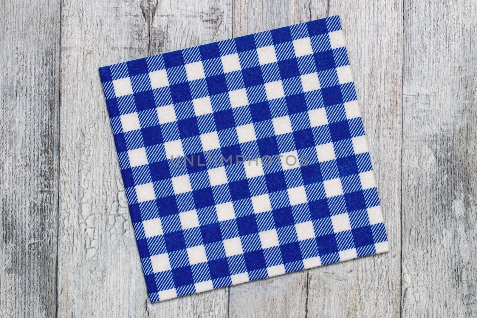 Empty table background. Top view of a empty blue and white checkered kitchen cloth, textile, tablecloth or napkin on a rustic bright gray table. Template for food and product display montage. Macro.