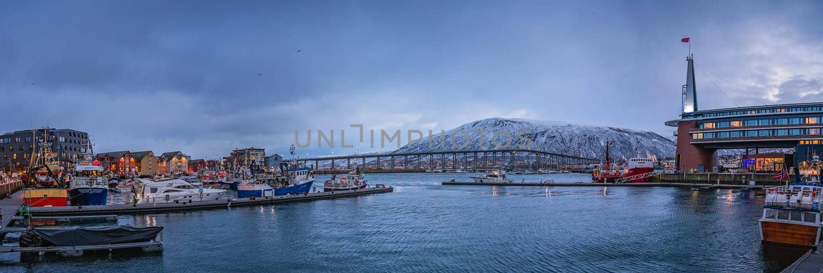 Tromso, Norway -  December 2018 : Port and harbour with famous Tromso Bridge across Tromsoysundet strait in the background