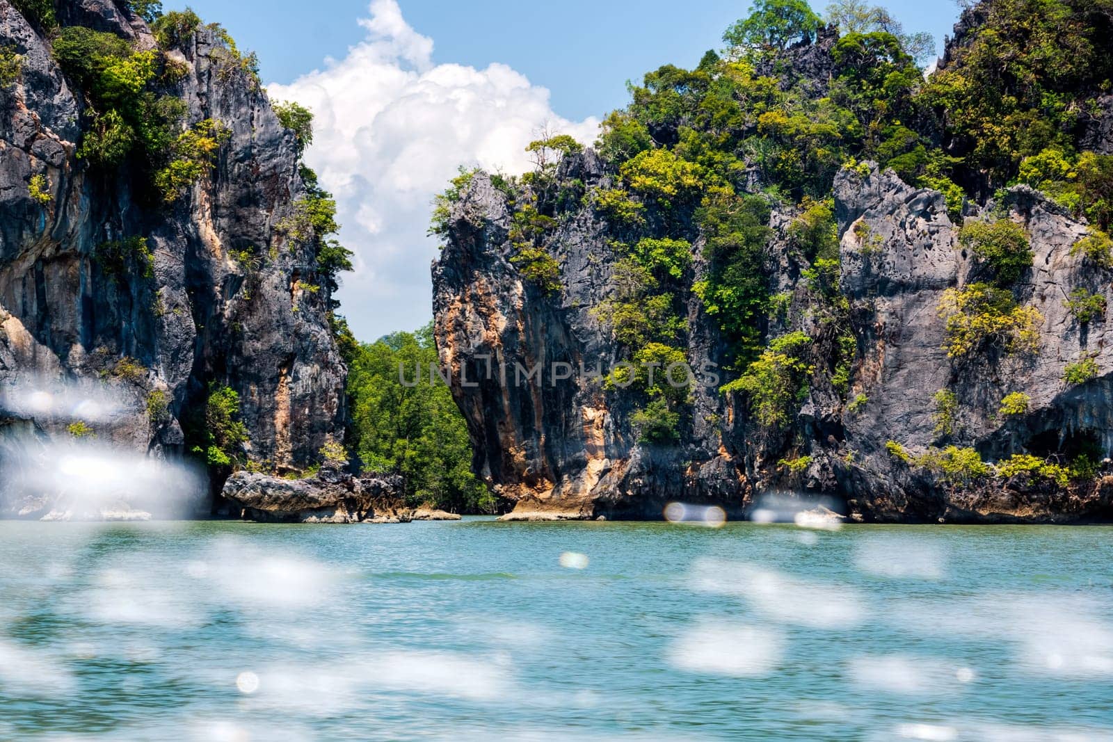 View on large cliffs and mountains of islands in Phang Nga archipelago, motion blurred splash of water from speed boat, Thailand