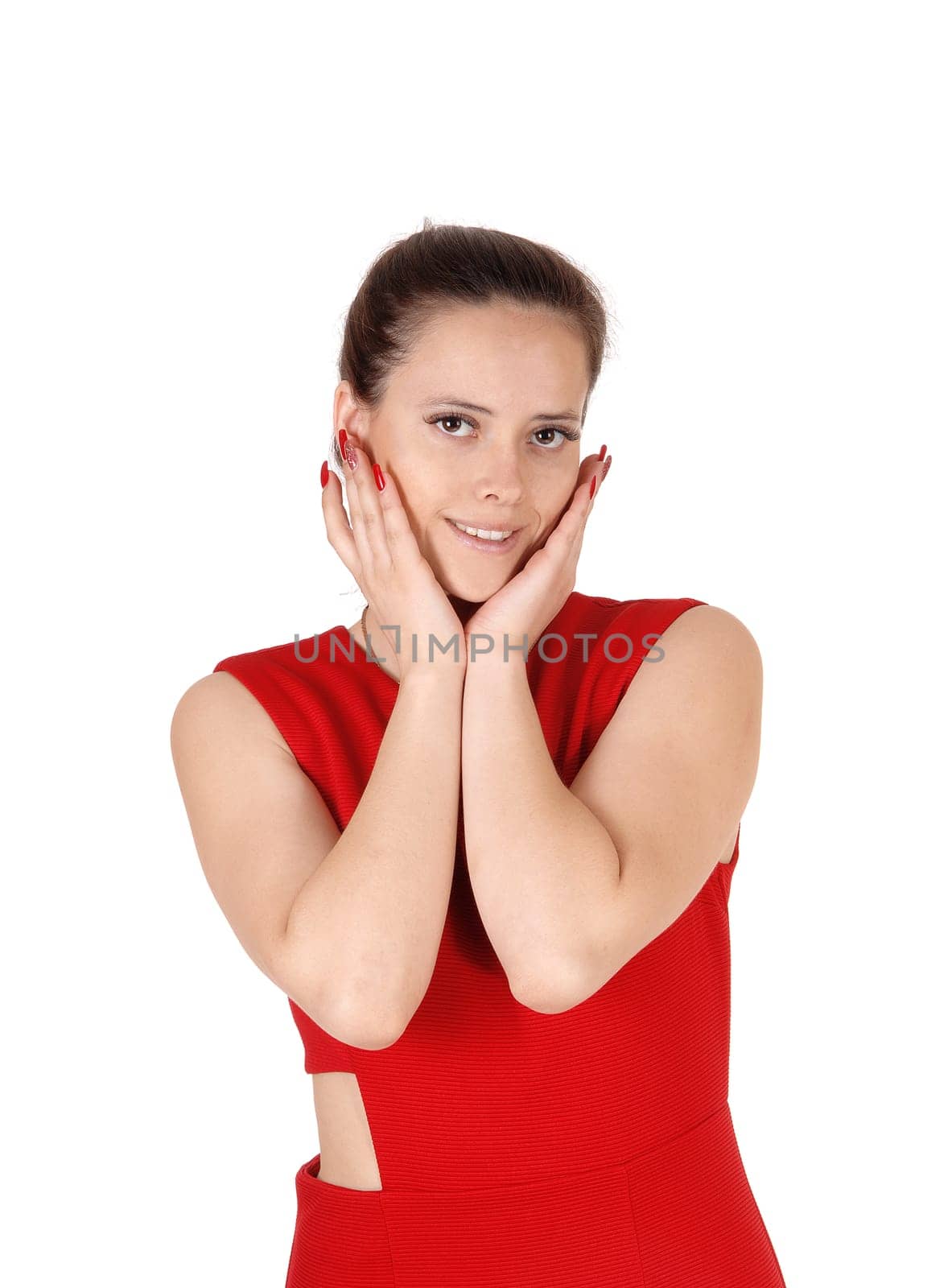 A happy smiling young woman standing in a red dress with both.hands on her face, smiling, isolated for white background.