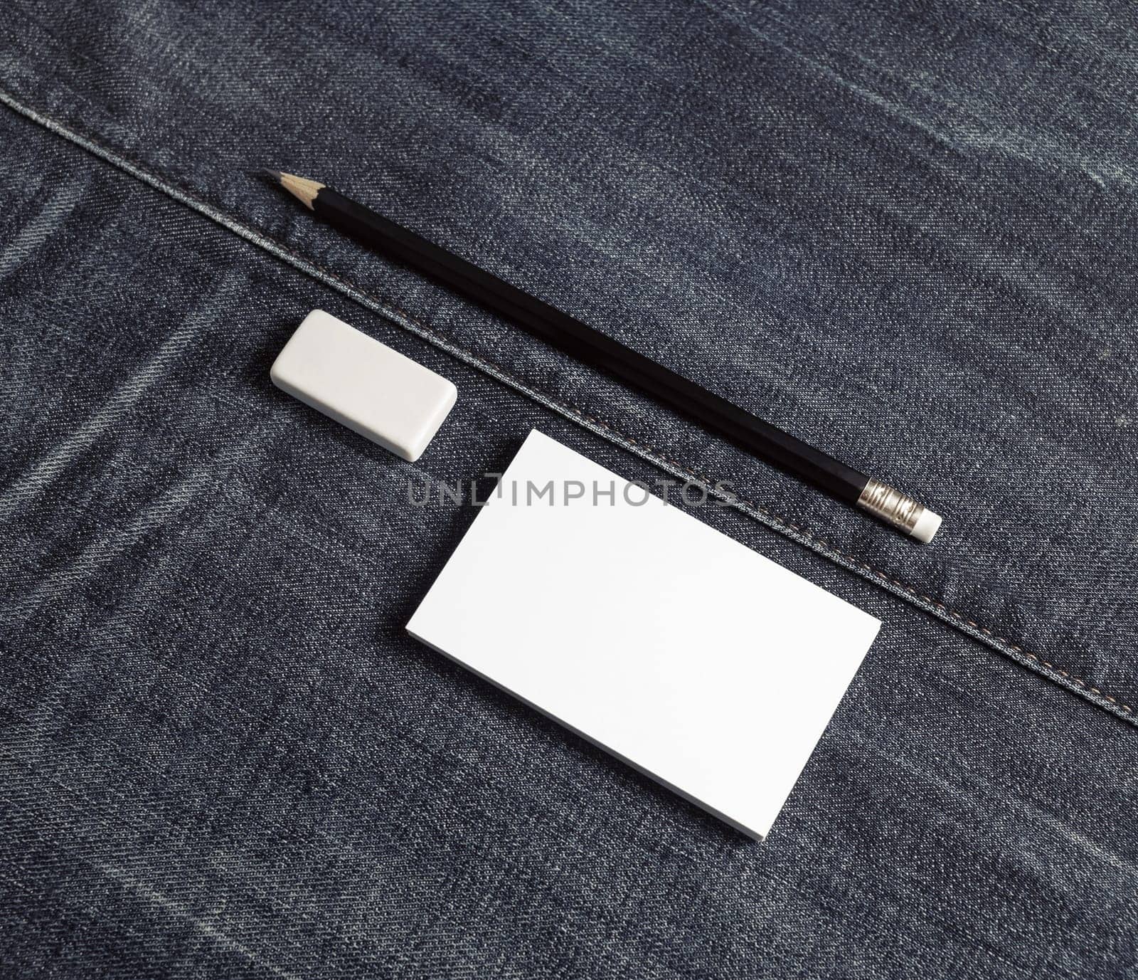 Photo of blank business card, pencil and eraser. Blank stationery set on denim background.