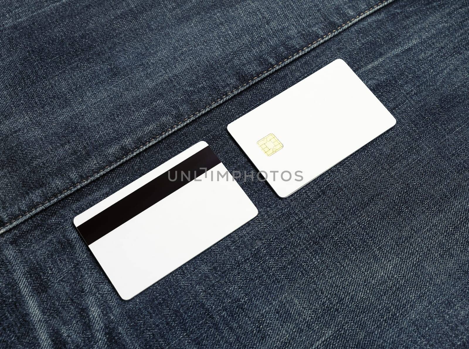 Two blank credit cards on denim background. Front and back view. Copy space for text.