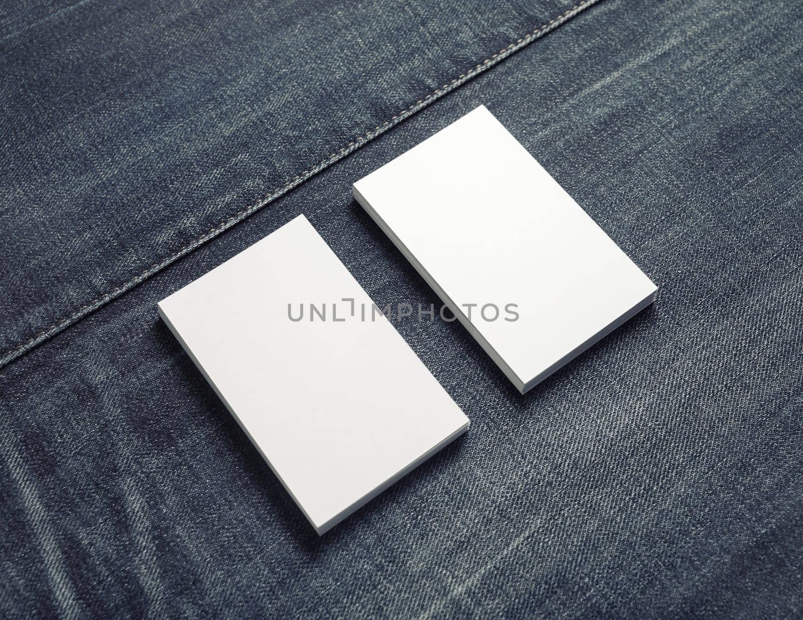 Mockup of two blank vertical business cards on denim background.