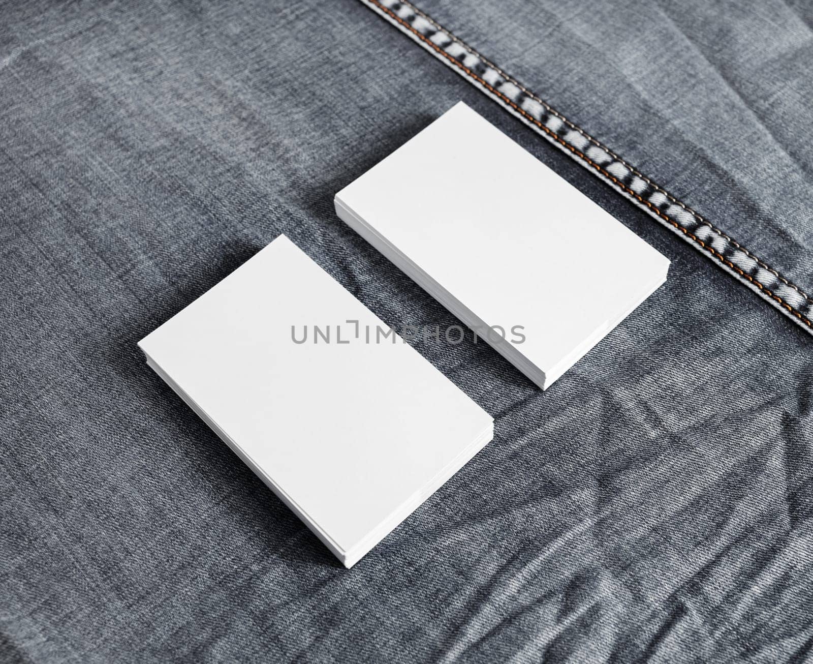 Blank name cards on gray denim background. White business cards template.