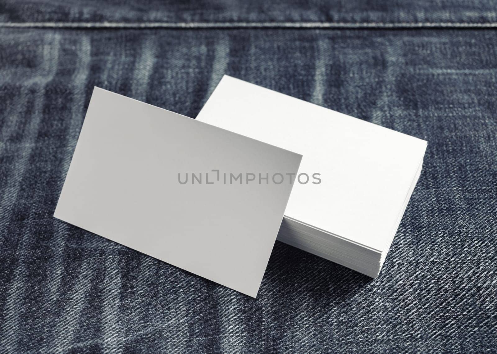 Photo of blank white business cards on denim background.