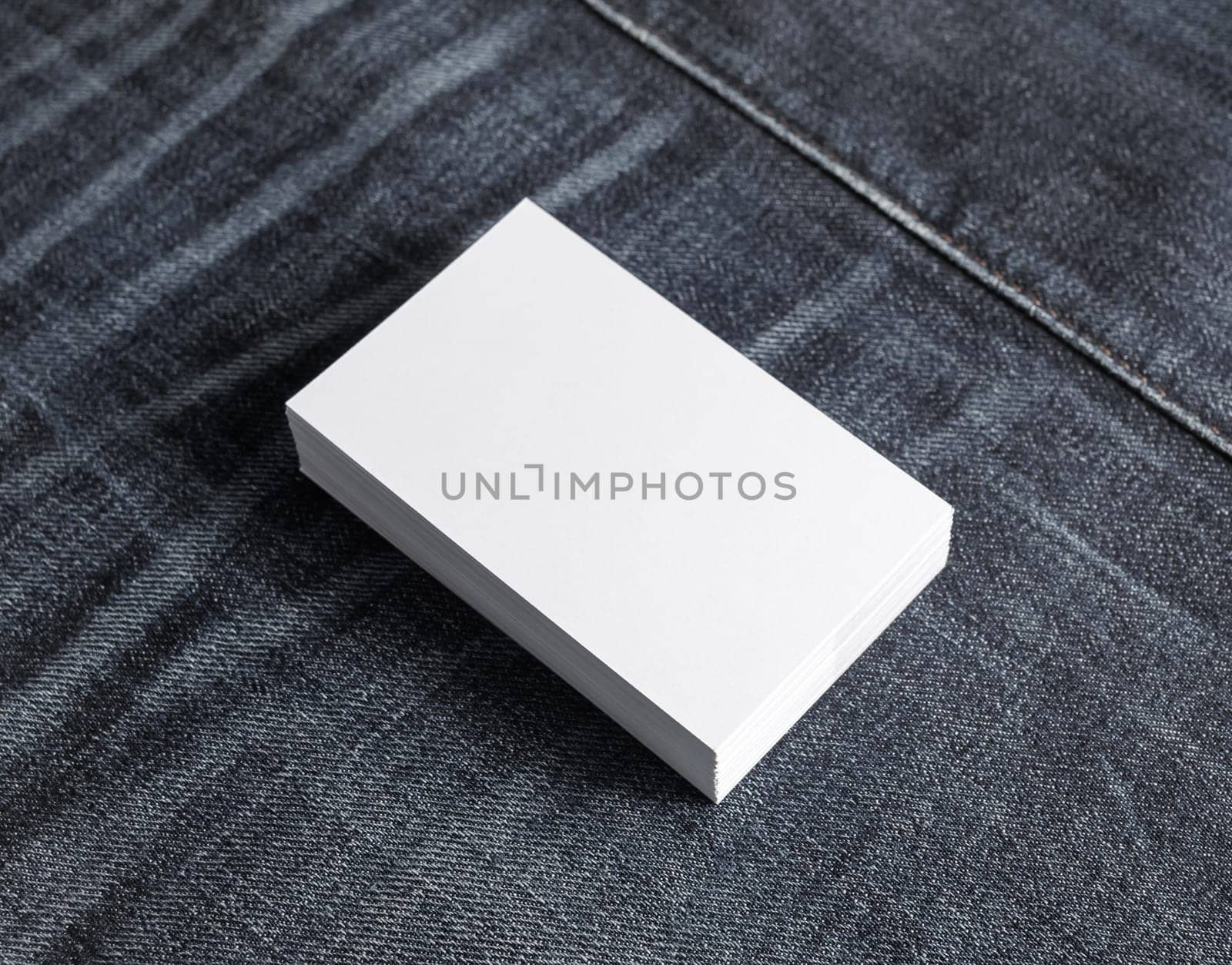 Photo of blank business cards stack on denim background.. Template for branding identity.