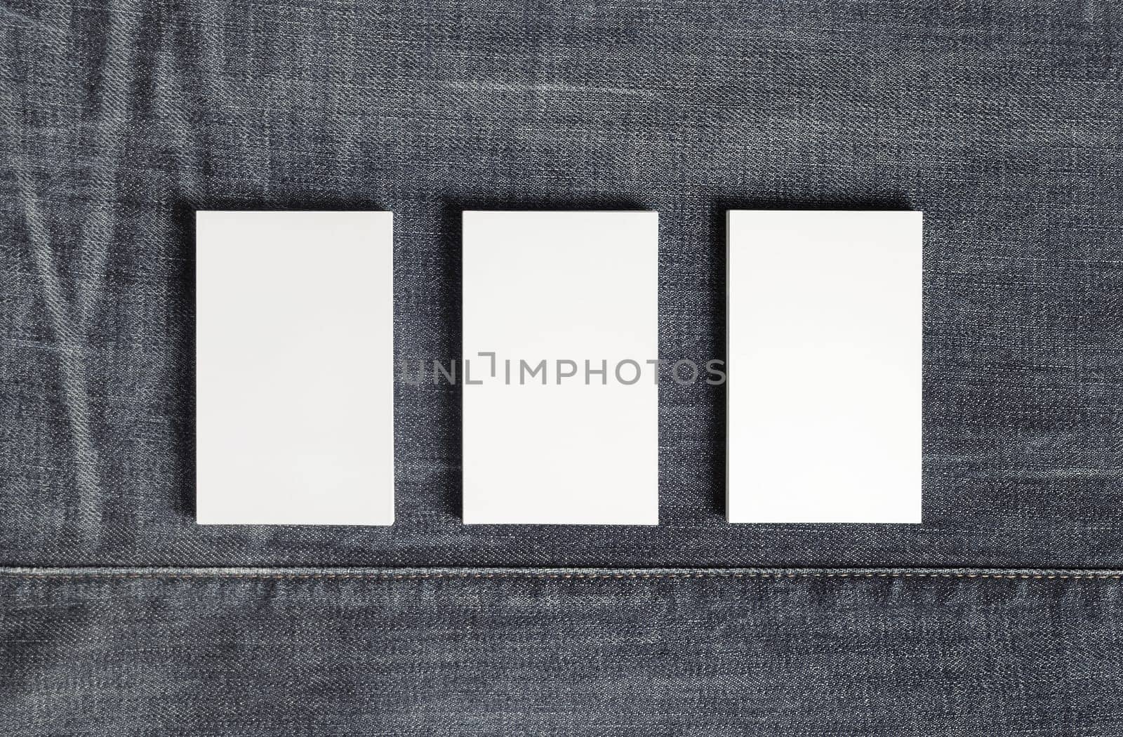Mockup of three blank vertical business cards on gray denim background. Copy space for text. Flat lay.