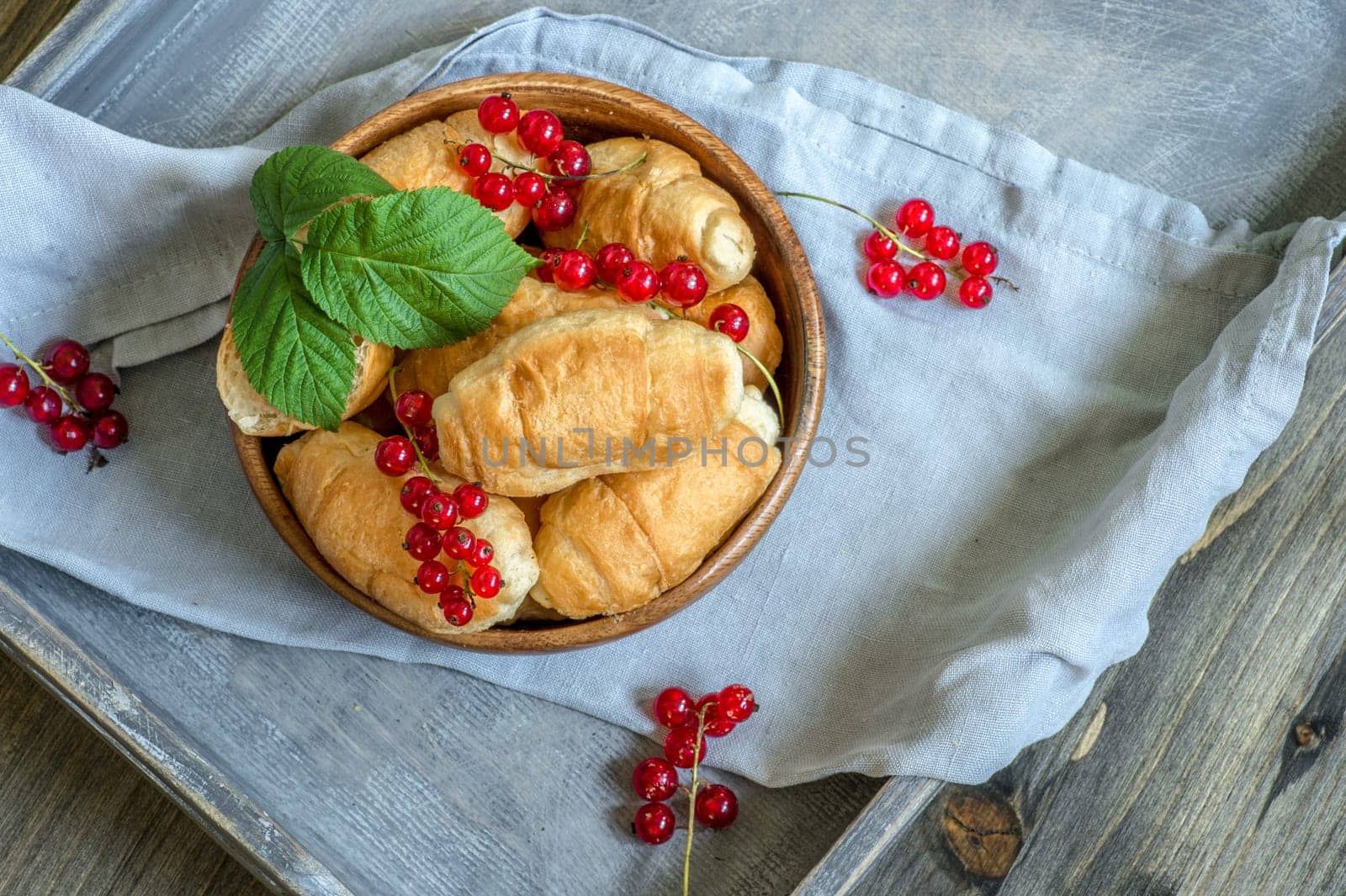 Croissants, a cup with kefir and ears of grain on a wooden tray. The concept of a wholesome breakfast