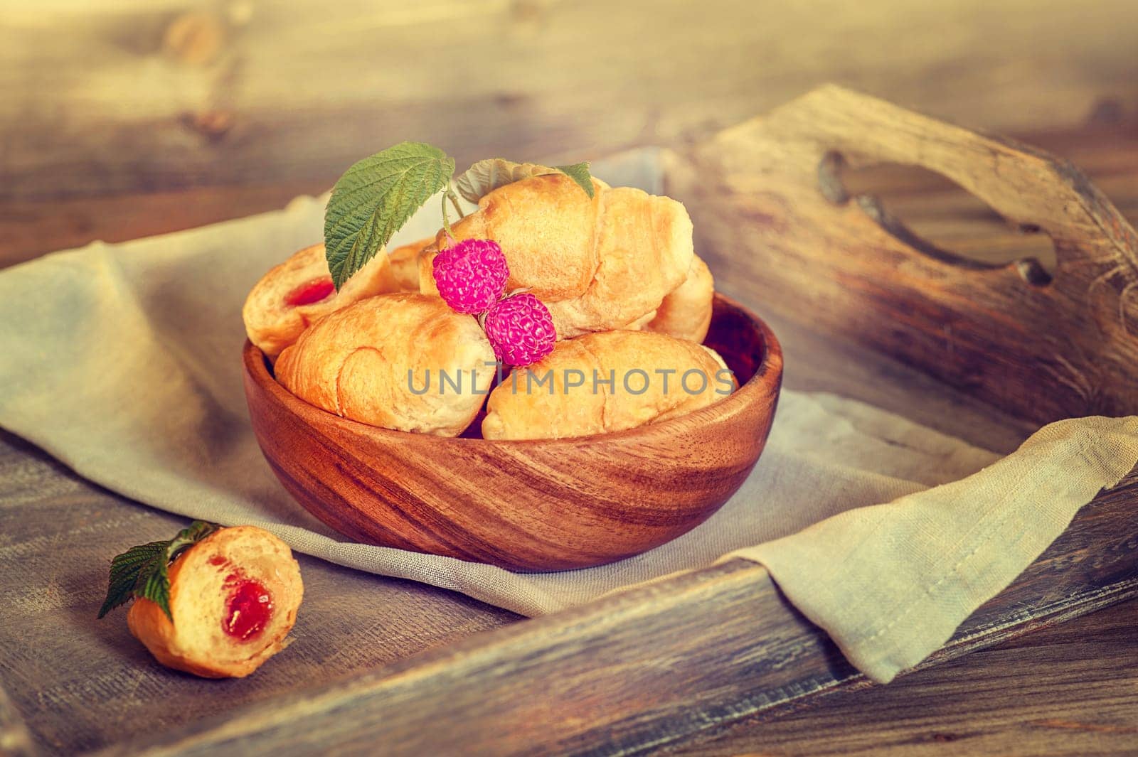 Croissants with raspberries on a wooden tray. The concept of a wholesome breakfast