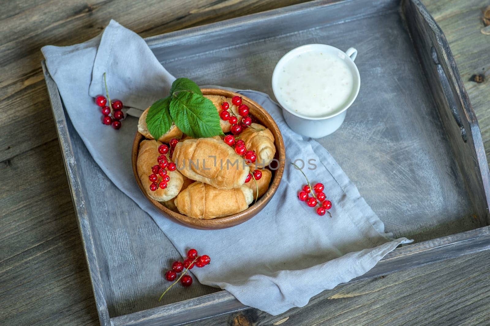 Croissants with currant berries on a wooden tray. The concept of a wholesome breakfast