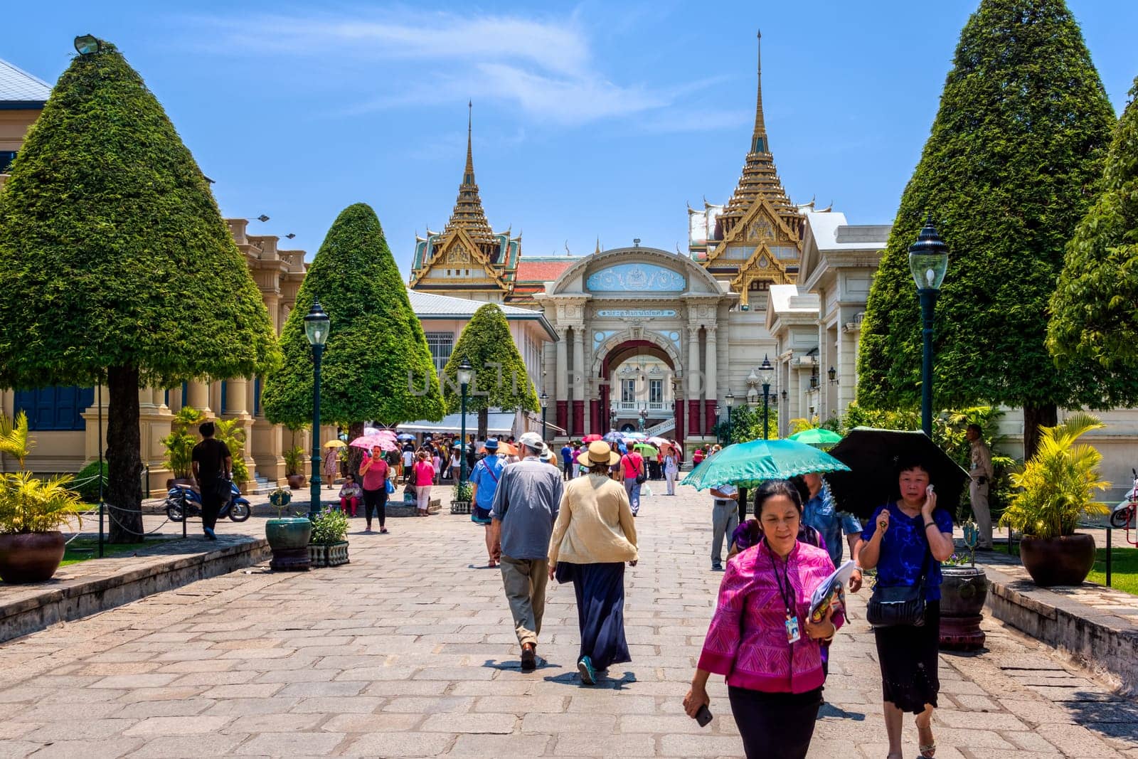 Bangkok, Thailand, March 2013 The Grand Palace entrance, visitors, people walking in and out, green trees and blue sky in background, front view