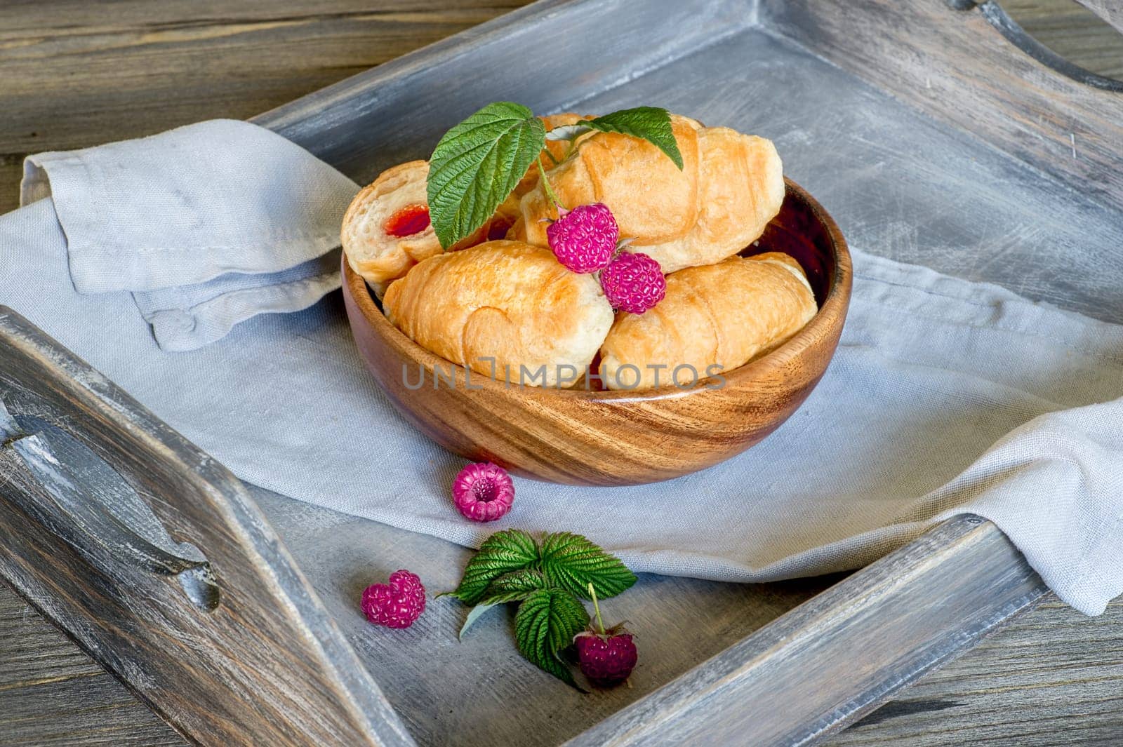 Croissants with currant berries on a wooden tray. The concept of a wholesome breakfast