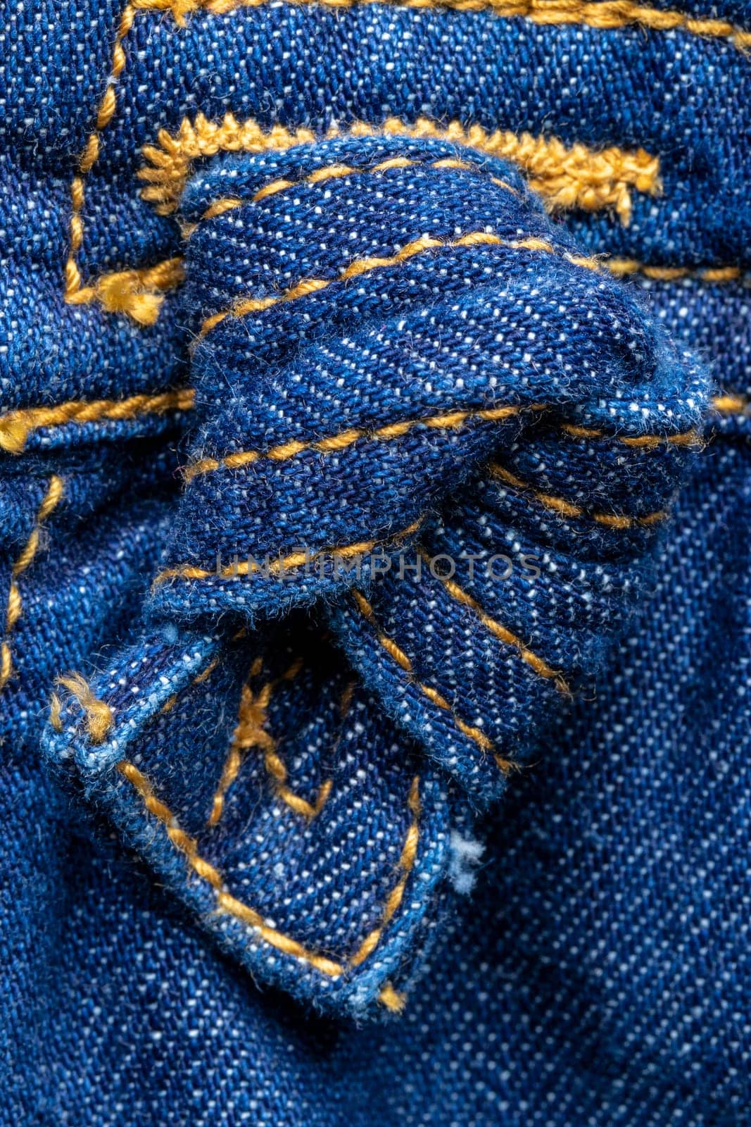 Denim decoration background. Close-up of a blue jeans knot or node at kids skirt as a decoration element. Macro.