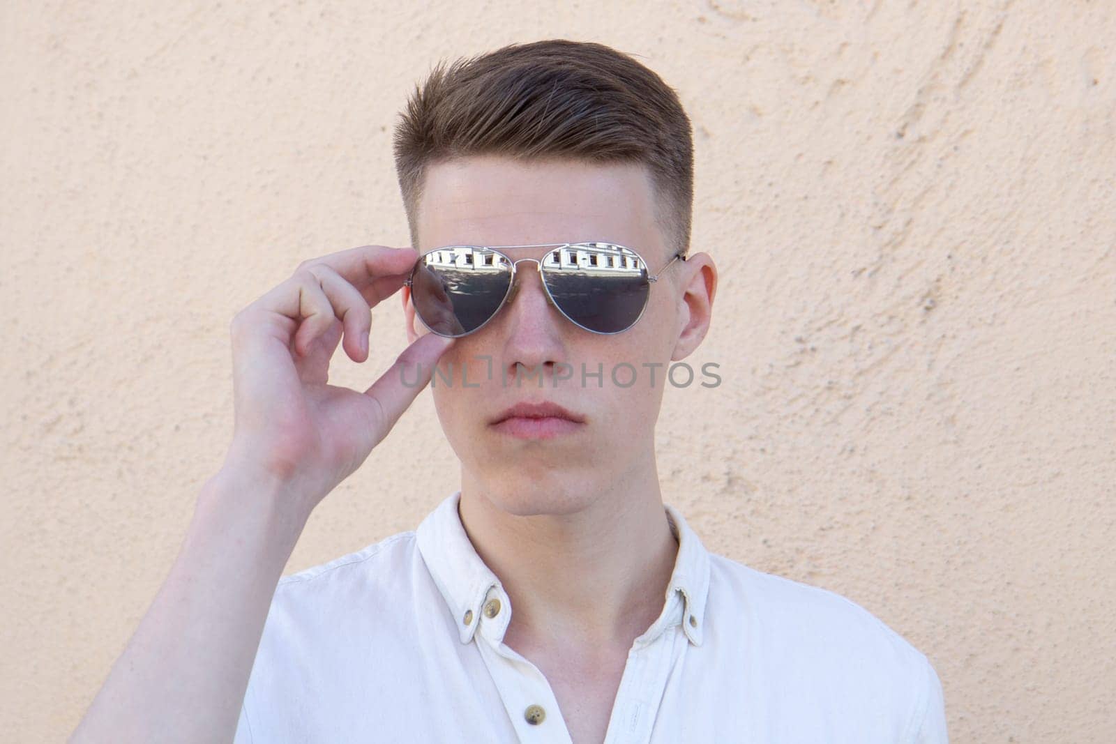 portrait of a handsome man dressed in white shirt against yellow wall