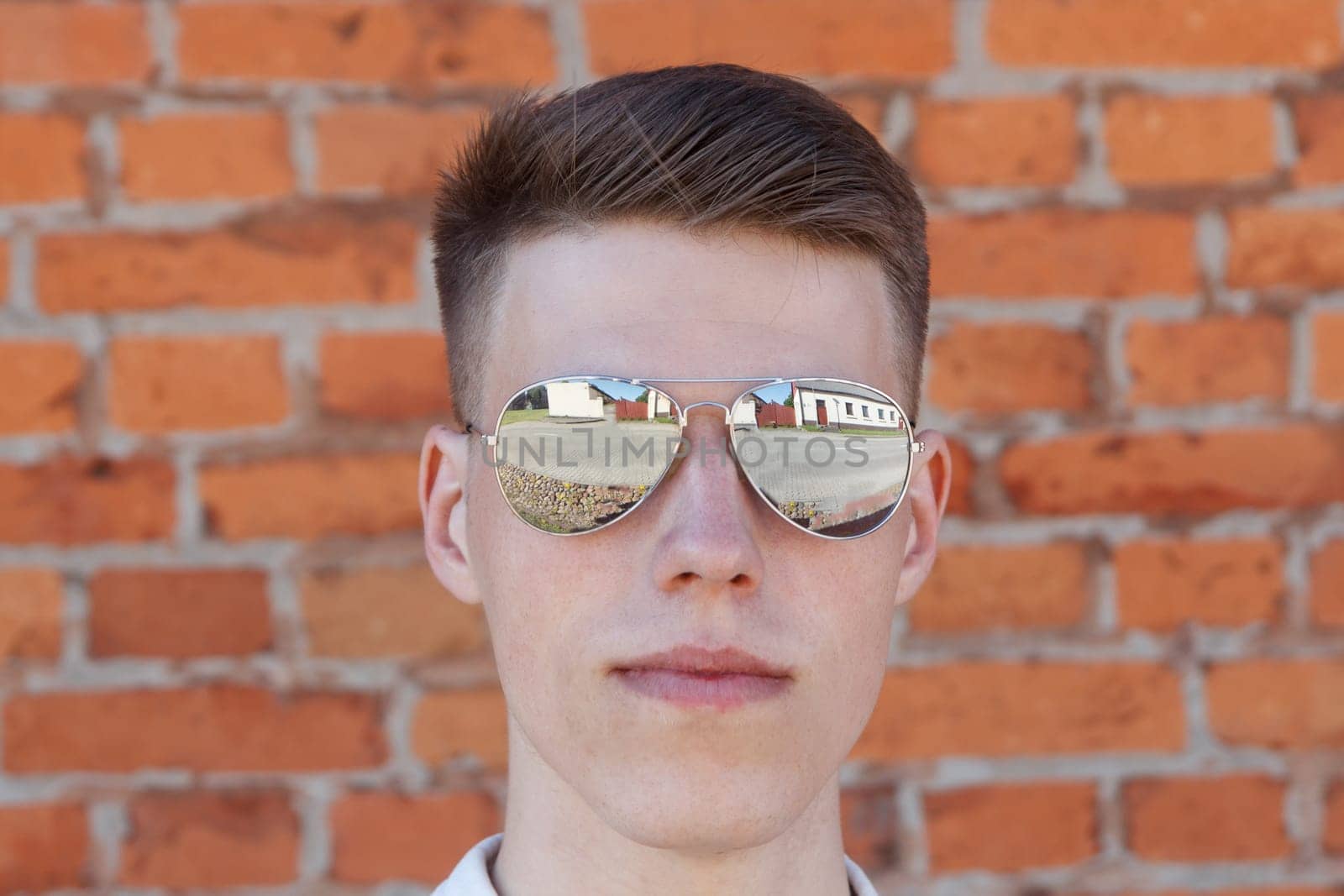 Portrait of a casually dressed young businessman standing against a brick wall