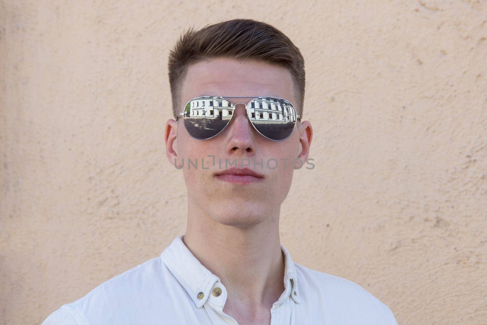 portrait of a handsome man dressed in white shirt against yellow wall