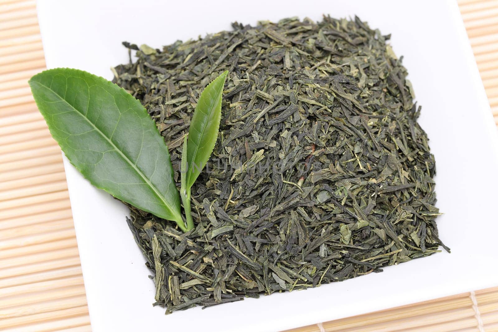Dried tea leaves with green tea leaves on bamboo background