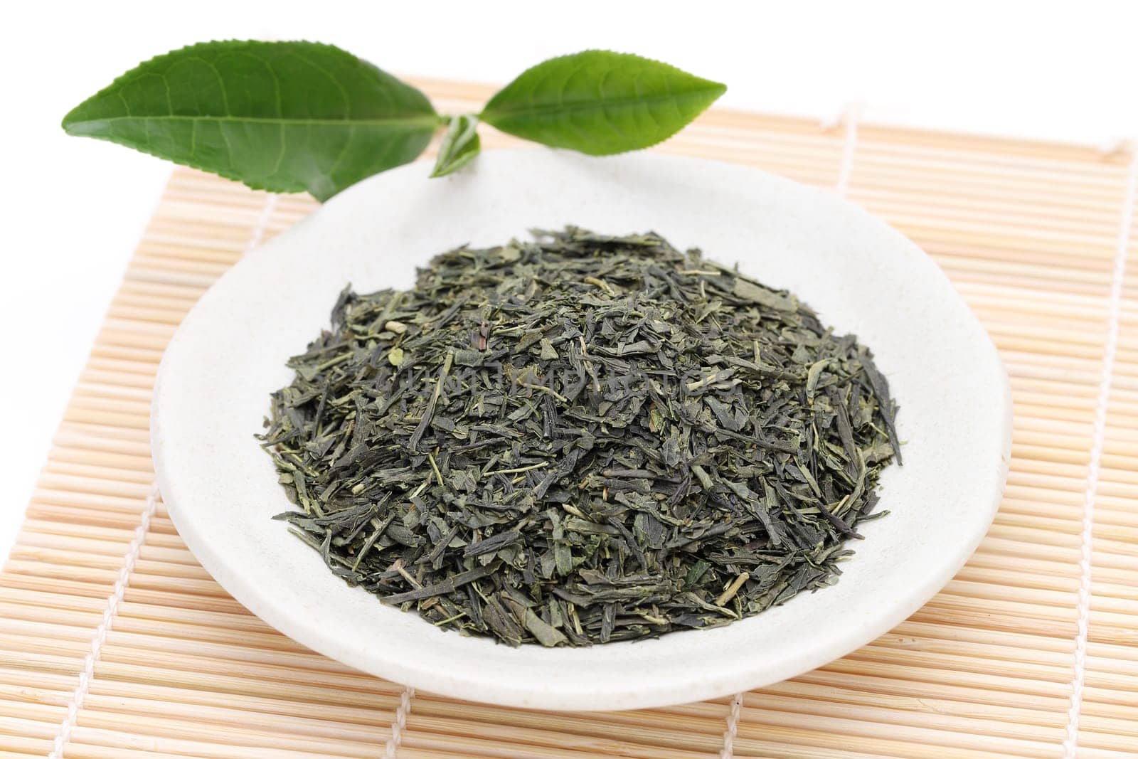 Dried tea leaves with green tea leaves on bamboo background