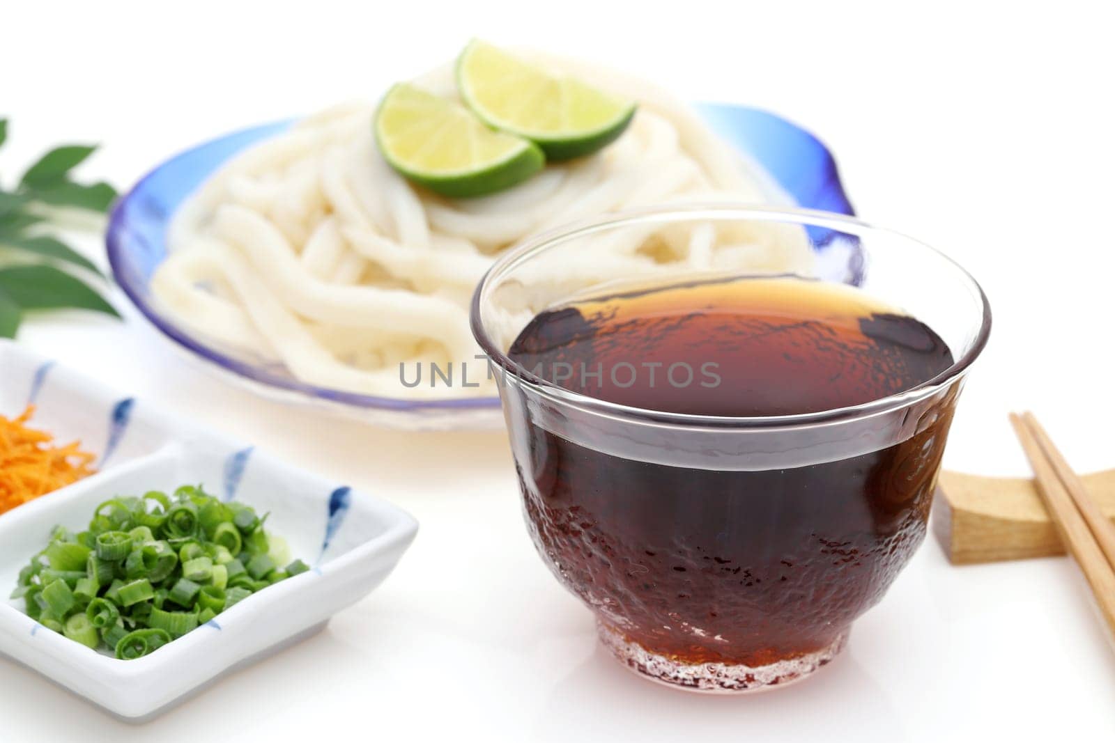 Japanese chilled udon noodles in a glass plate with soy sauce on white background