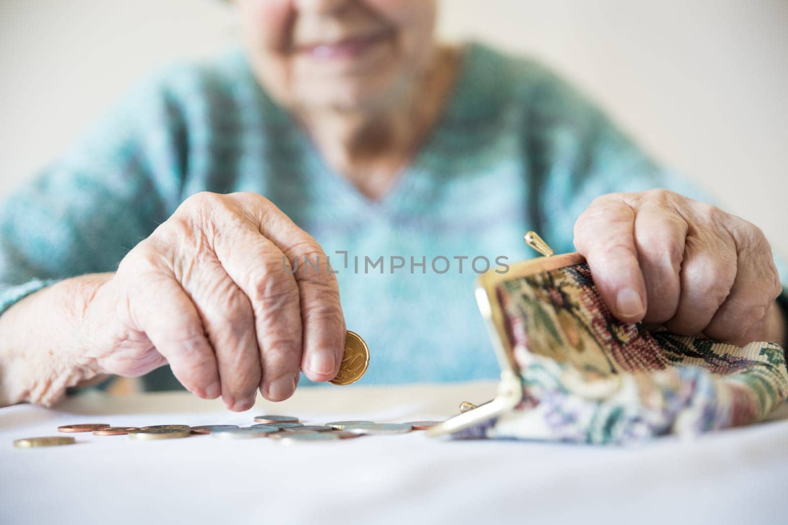 Detailed closeup photo of elderly 96 years old womans hands counting remaining coins from pension in her wallet after paying bills. Unsustainability of social transfers and pension system.