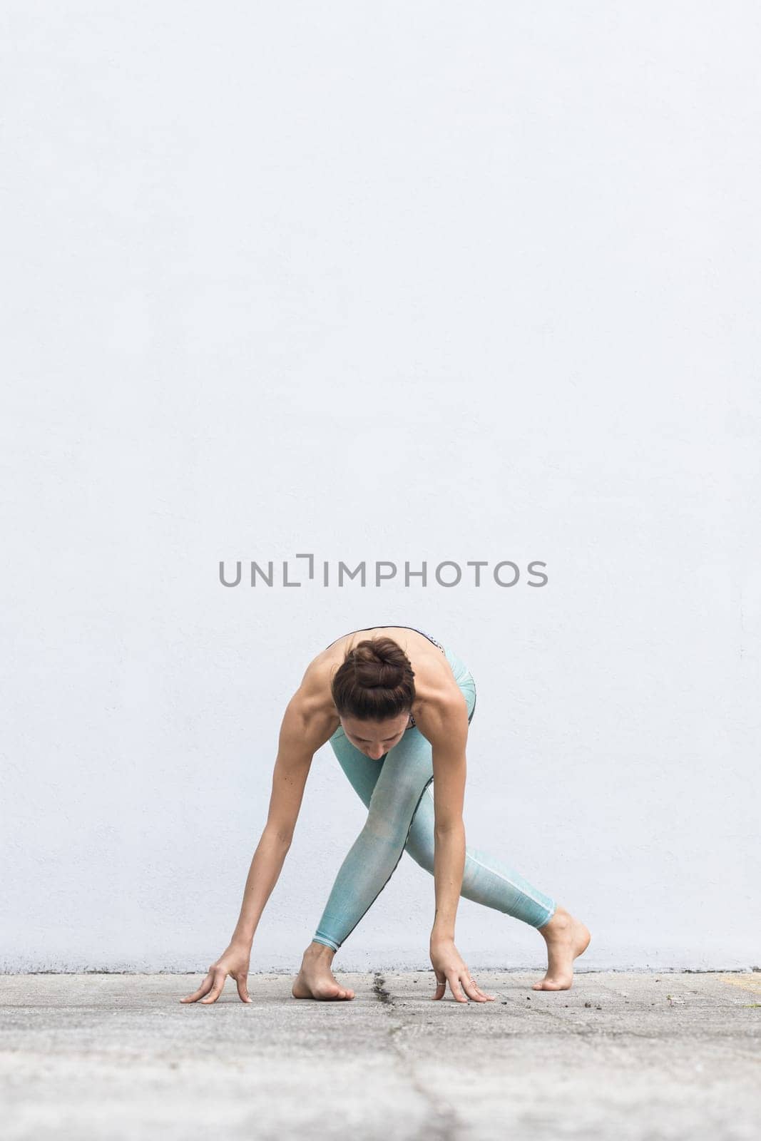 Fit sporty active girl in fashion sportswear doing yoga fitness exercise in front of gray wall, outdoor sports, urban style.