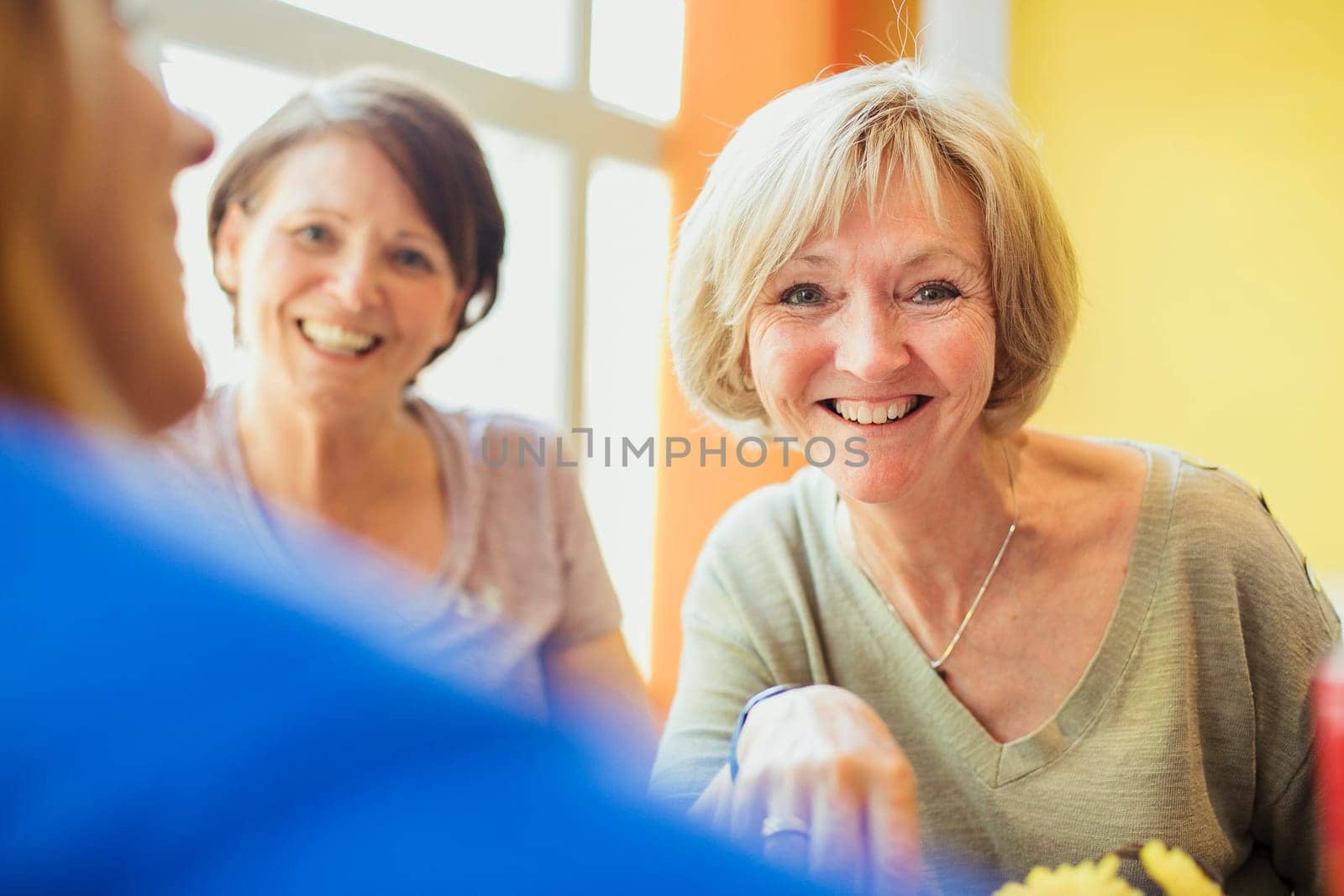 A close-up shot of two mature female friends sitting in a cafè.