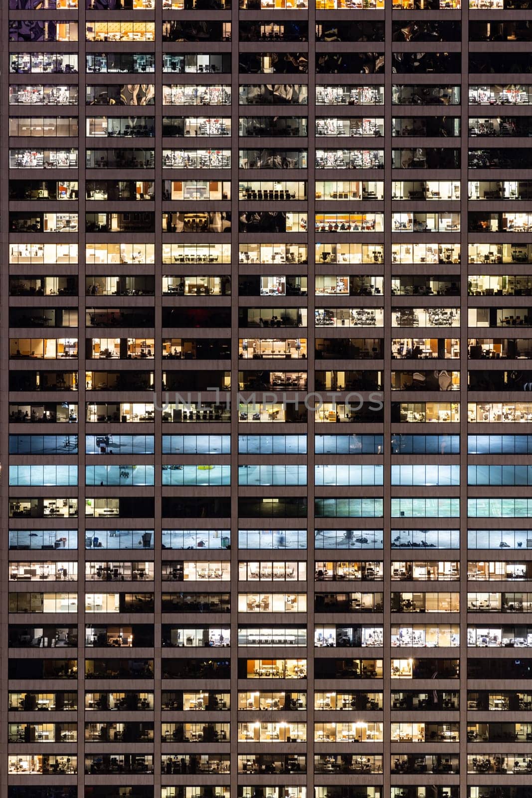 Late Working urban concept, window facade of business center office building at night, New York city NY USA