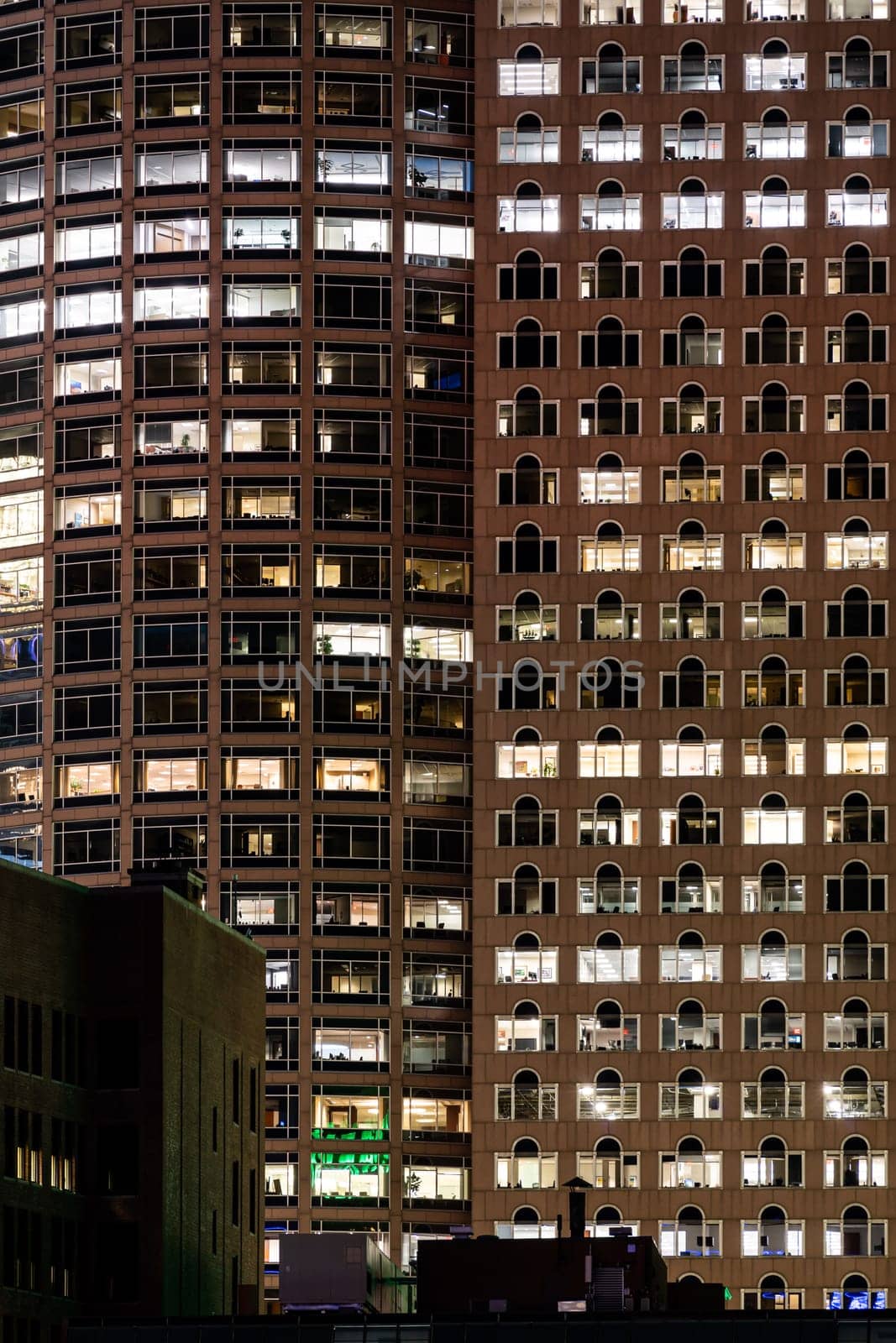 Late Working urban concept, window facade of business center office building at night, Boston, MA, USA.