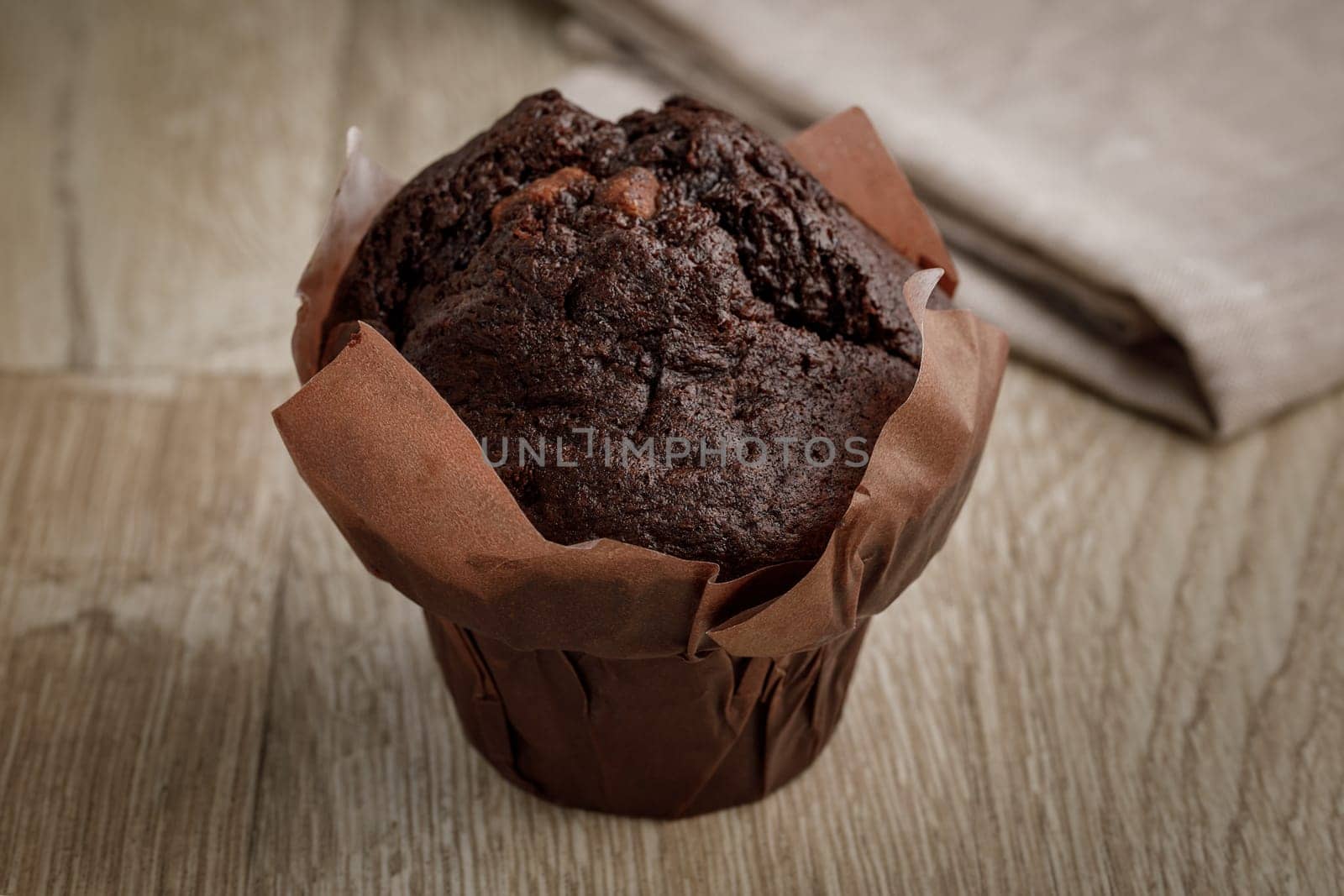 Chocolate cake in baking paper on a wooden surface