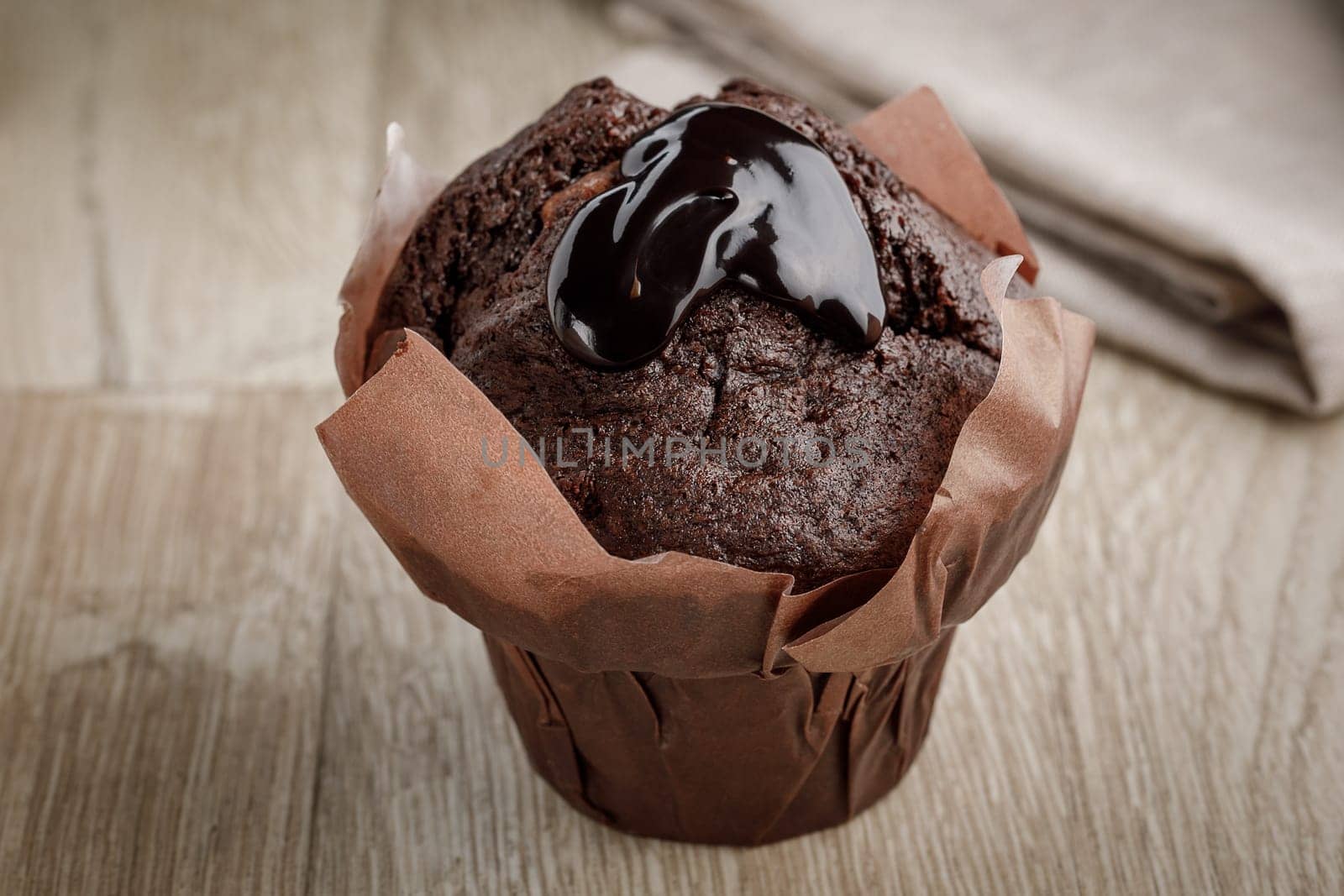 Chocolate cake in baking paper on a wooden surface, and with chocolate coating