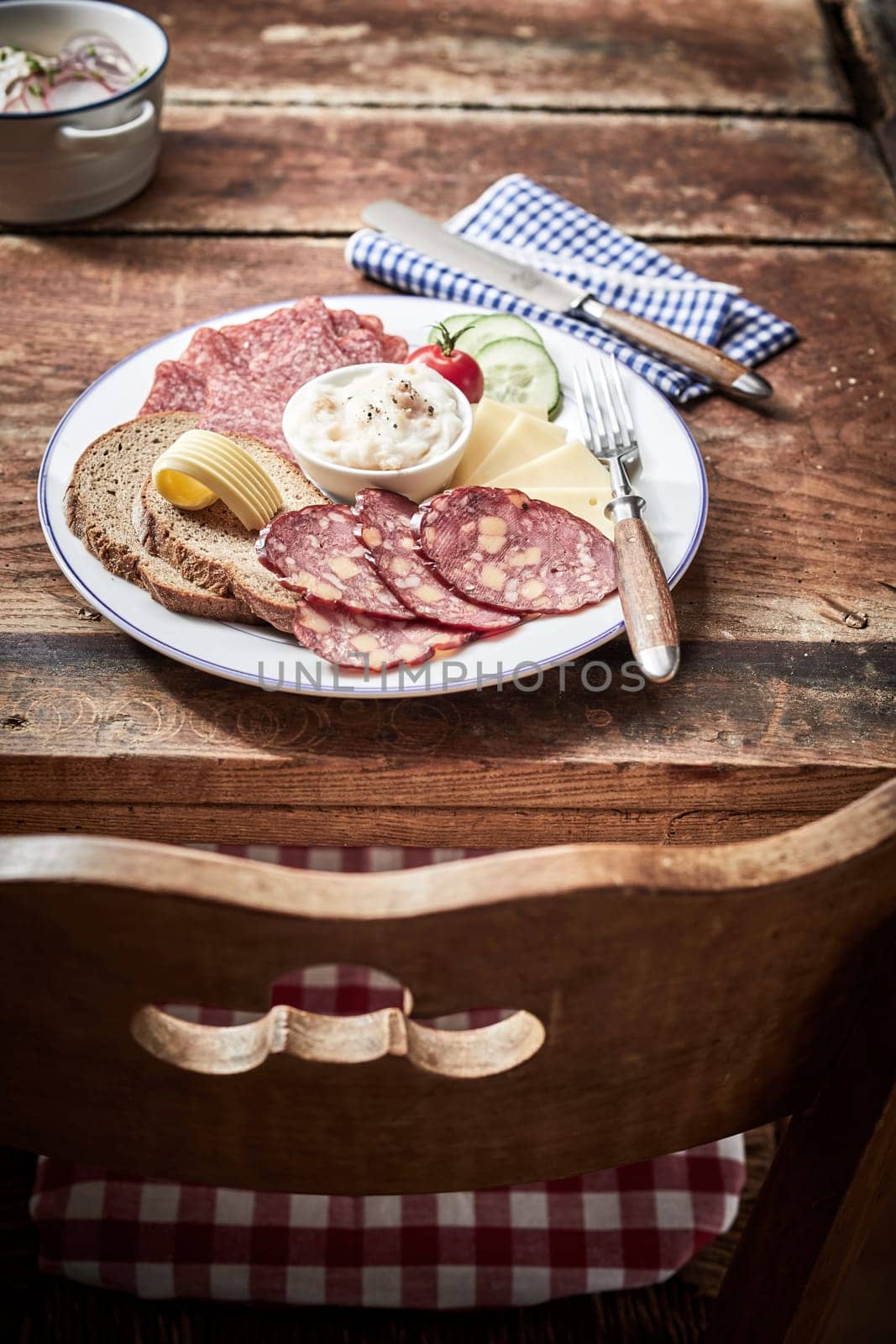 Tasty lunch platter with cheese and dried and cured wild venison sausage, rye bread and a creamy dip or spread on an old rustic table