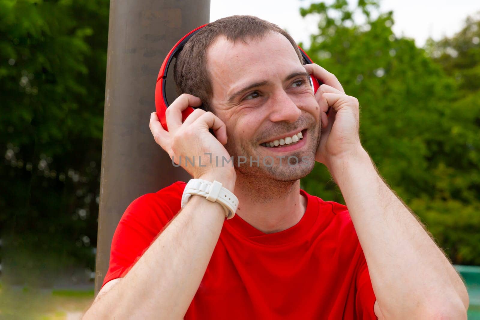 Young joyful Sportsman with red headphones in nature