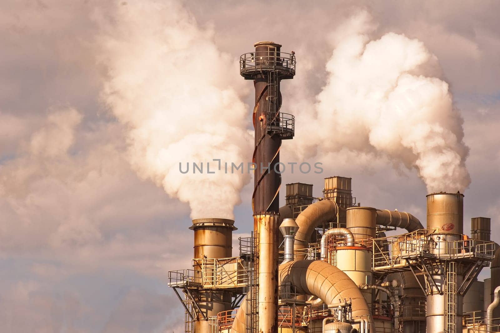 Industrial plant with smoking smokestack,tube,silos.