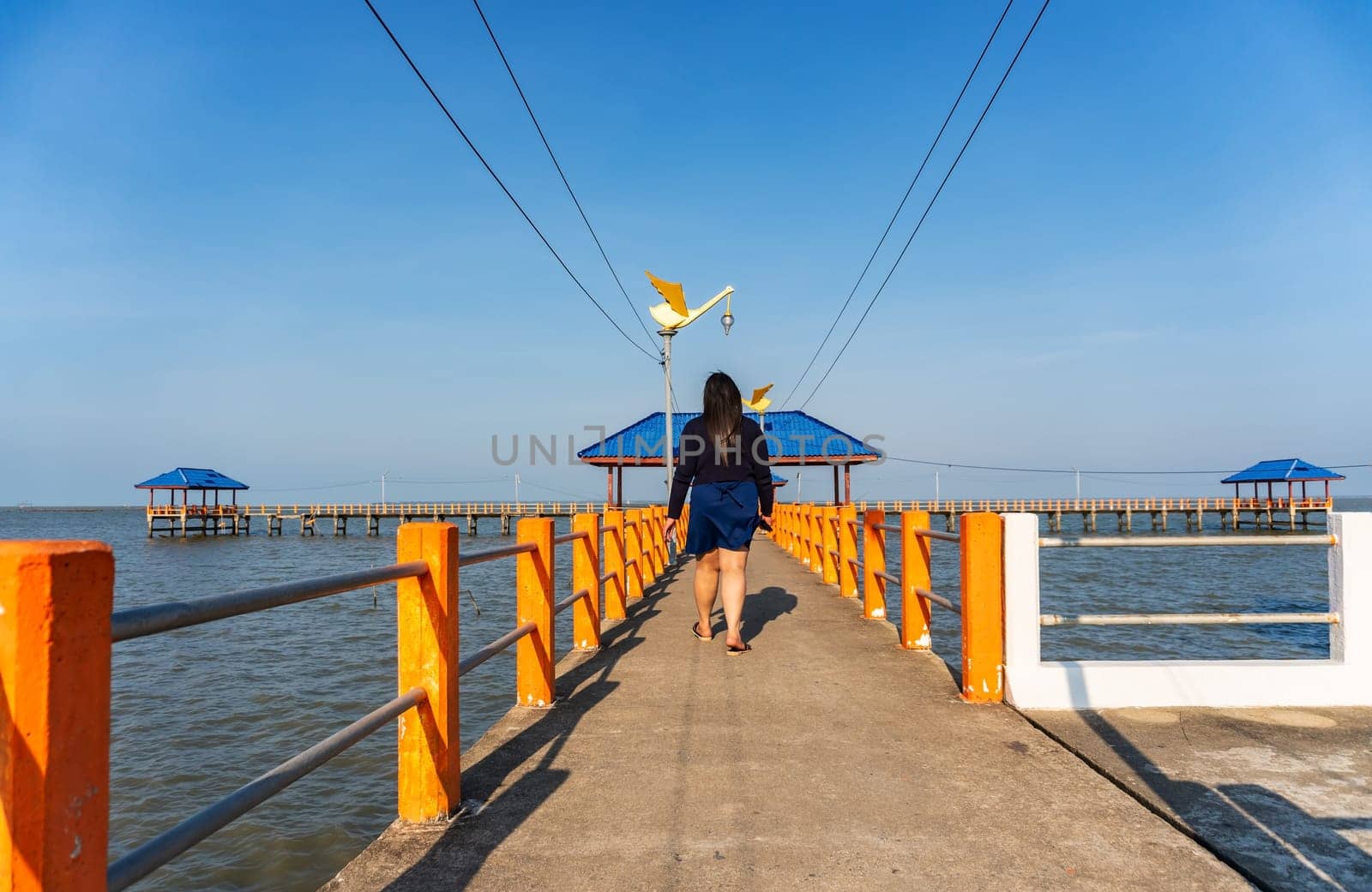 Some people walking on the bridge in the blue sea in evening light