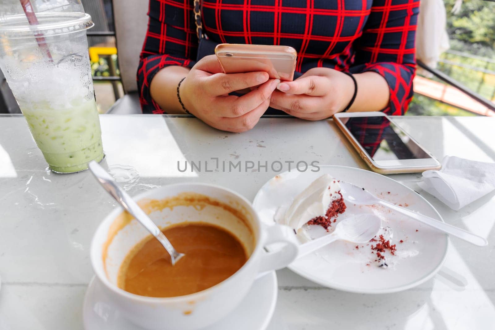 Young women using smart phone social network with cappuccino coffee and ice milk green tea and chocolate cake depleted in coffee shop relaxation concept