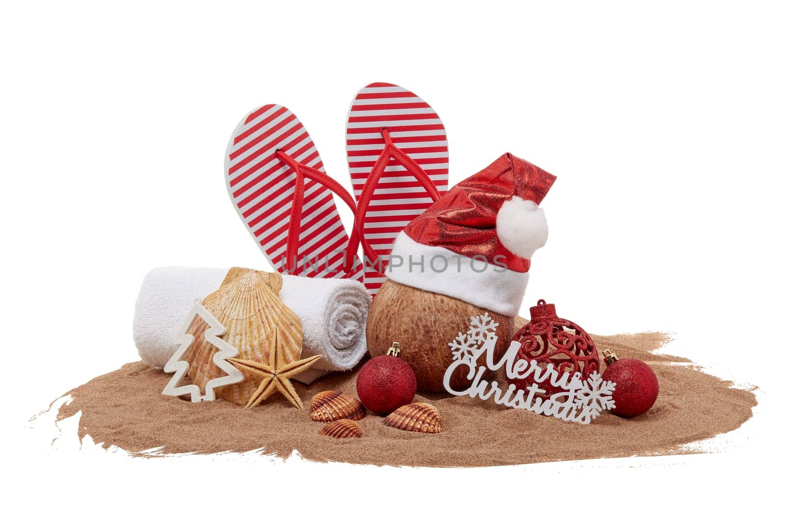 Still life with beach accessories (flip flops, towel, seashells, sand, coconut) and christmas ornaments on white background. Christmas. Winter vacation in warm countries, beach holiday