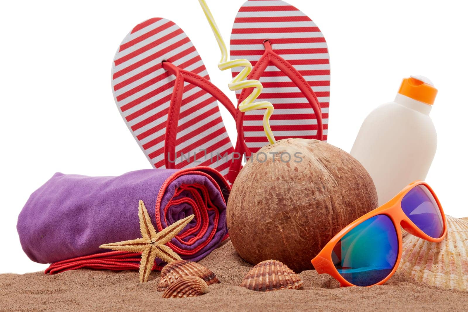 Beach accessories: flip flops, sunglasses, sunscreen, towel, seashells, coconut drink, lying on the sand on white background. Concept of sea vacation and travel. Summer background, Protection from uv