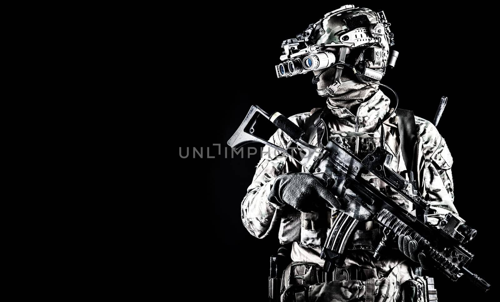 Half length portrait of army special forces rifleman, commando elite soldier equipped radio tactical headset, armed service rifle, using night vision goggles in darkness, isolated on black, copyspace