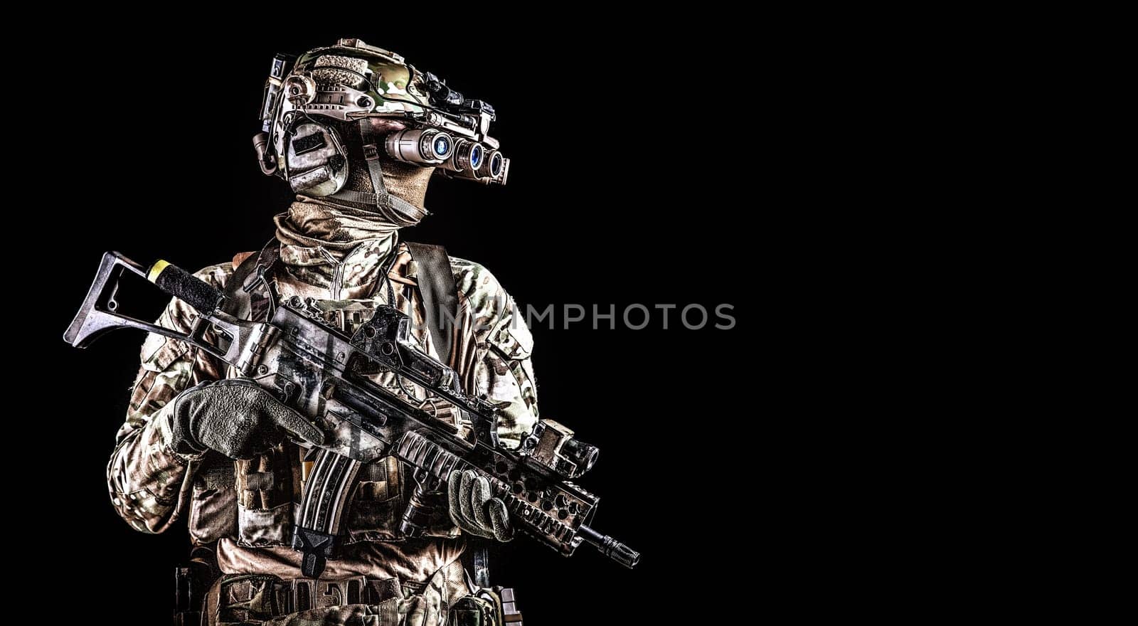 Half length portrait of army special forces rifleman, commando elite soldier equipped radio tactical headset, armed service rifle, using night vision goggles in darkness, isolated on black, copyspace