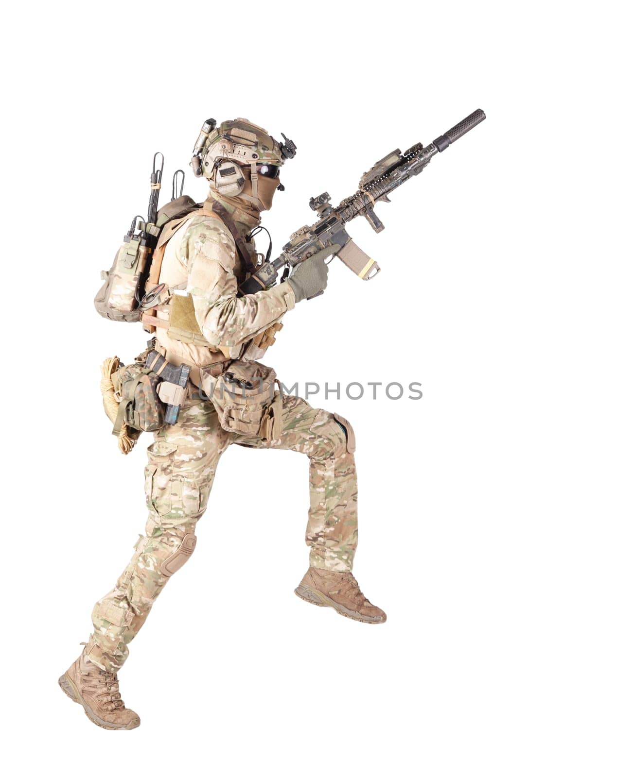 Army soldier, equipped infantryman, airsoft player in camouflage battle uniform, helmet and tactical radio headset jumping, running with assault rifle in hand studio shoot isolated on white background