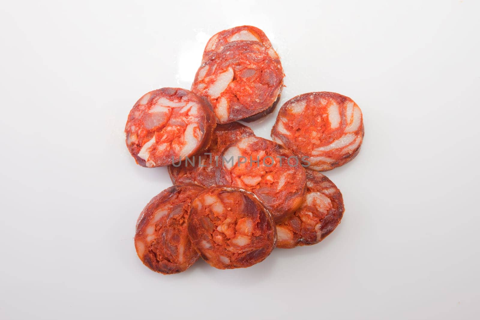 Some cut pieces of red iberian chorizo. Isolated over white background