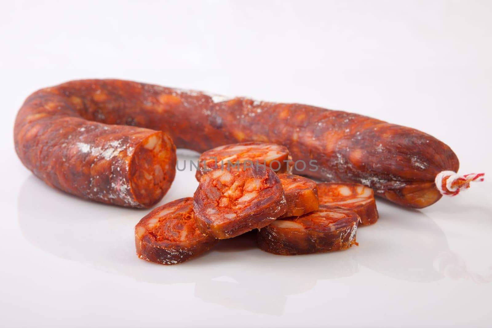 Red iberian chorizo with some cut pieces. Isolated over white background