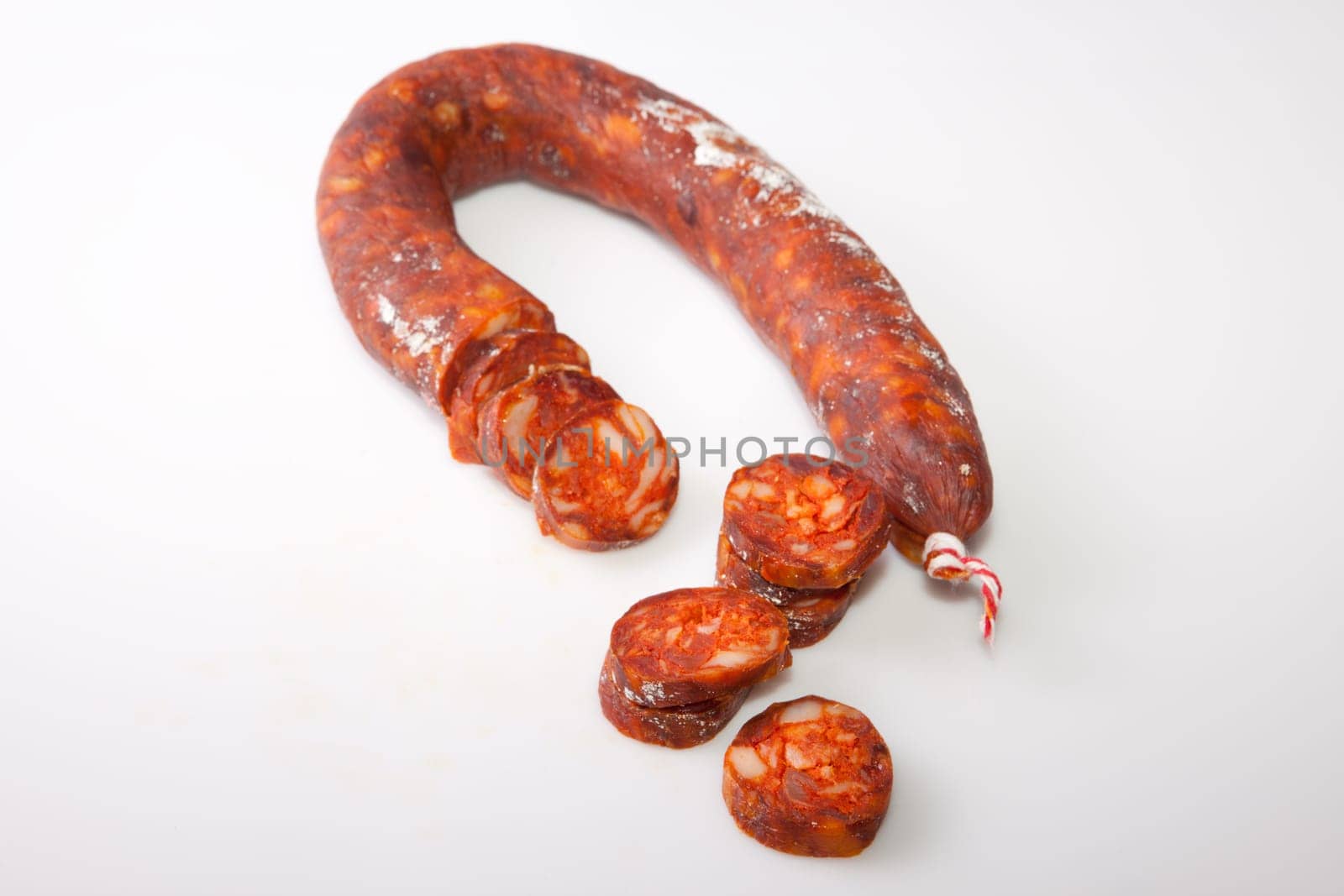 Red iberian chorizo with some cut pieces. Isolated over white background