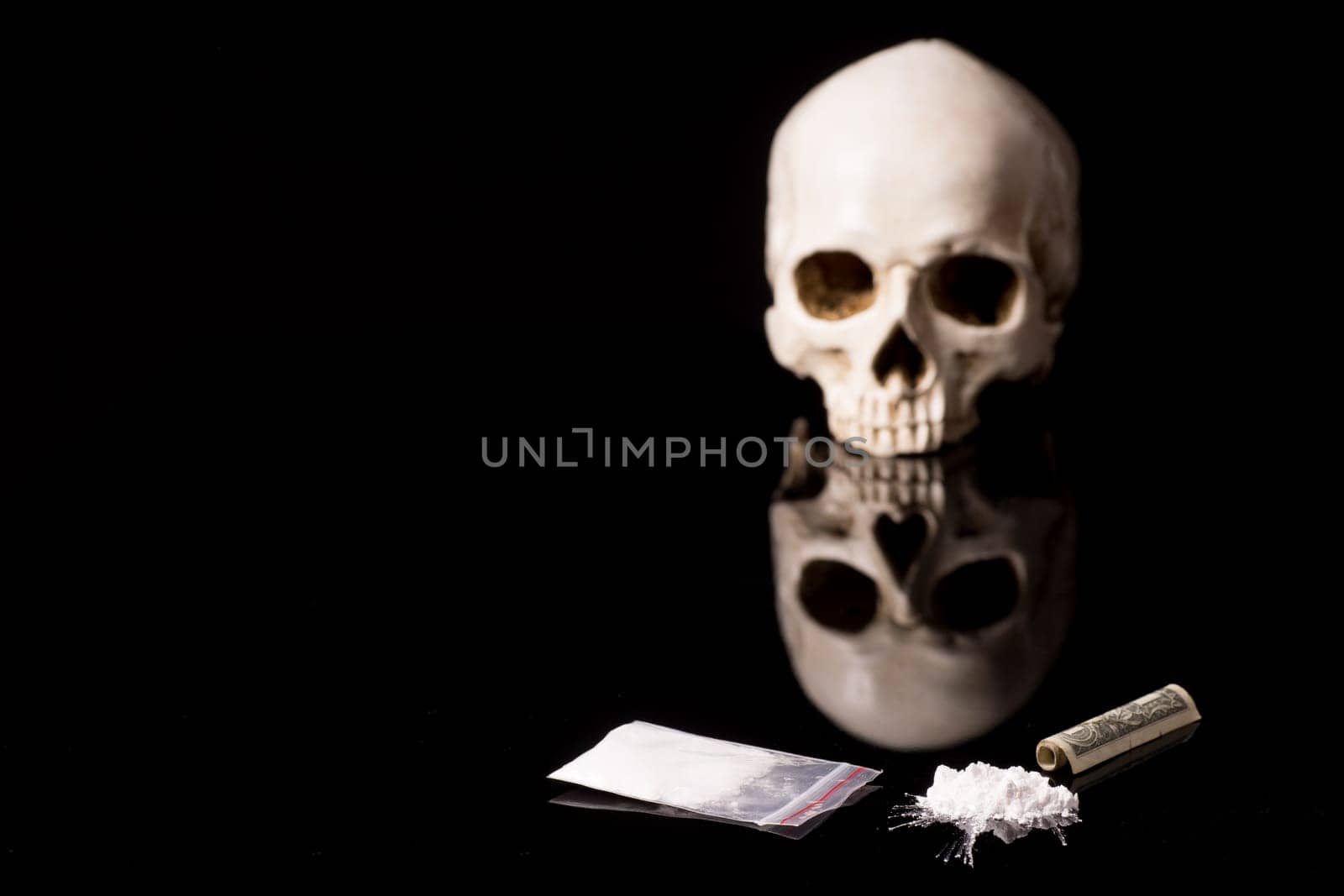 cocaine, Herion or other illegal drugs that are sniffed by means of a tube or injected with a syringe, money and Skull, isolated on black glossy background