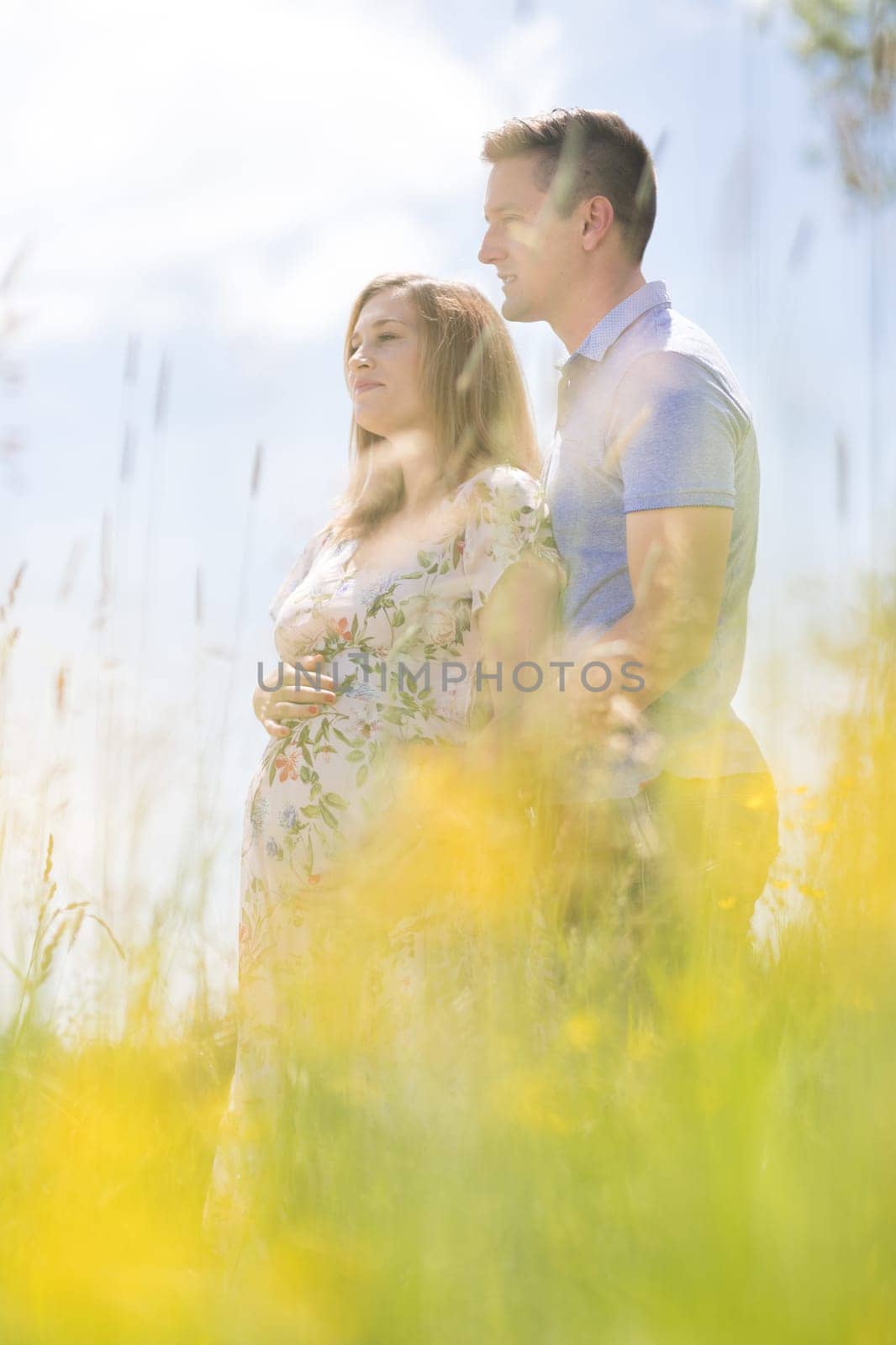 Young happy pregnant couple hugging in nature. Concept of love, relationship, care, marriage, family creation, pregnancy and parenting.